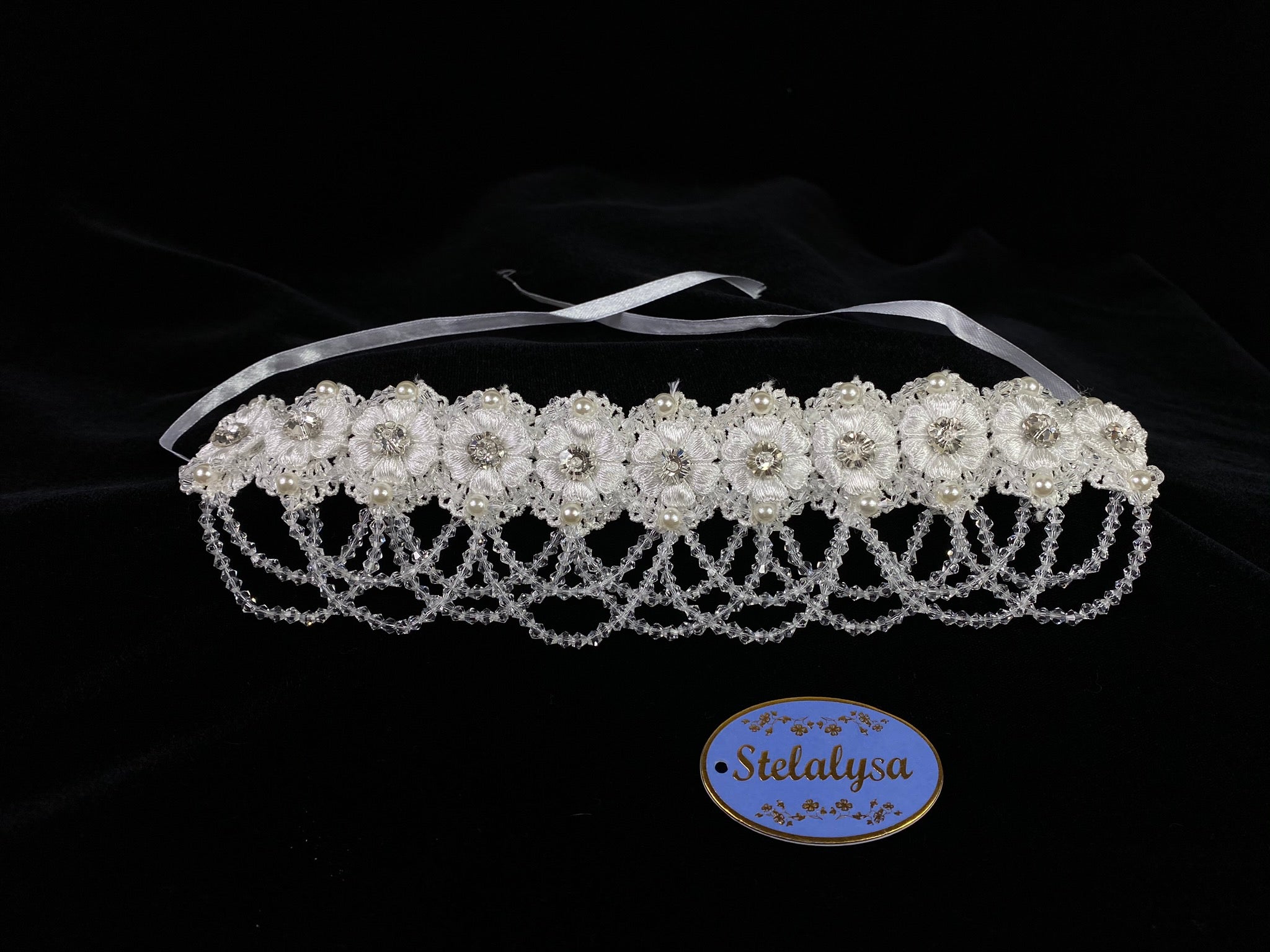 A must have for the First Communion!   Beautiful headband applique with pearl and crystal detailing, along embroidered flower band.  Headband is 12" long, to tie beautifully around the head.   The headband ties with two satin ribbons giving it an elegant look.   This headband can be worn with any of the First Communion dresses. 