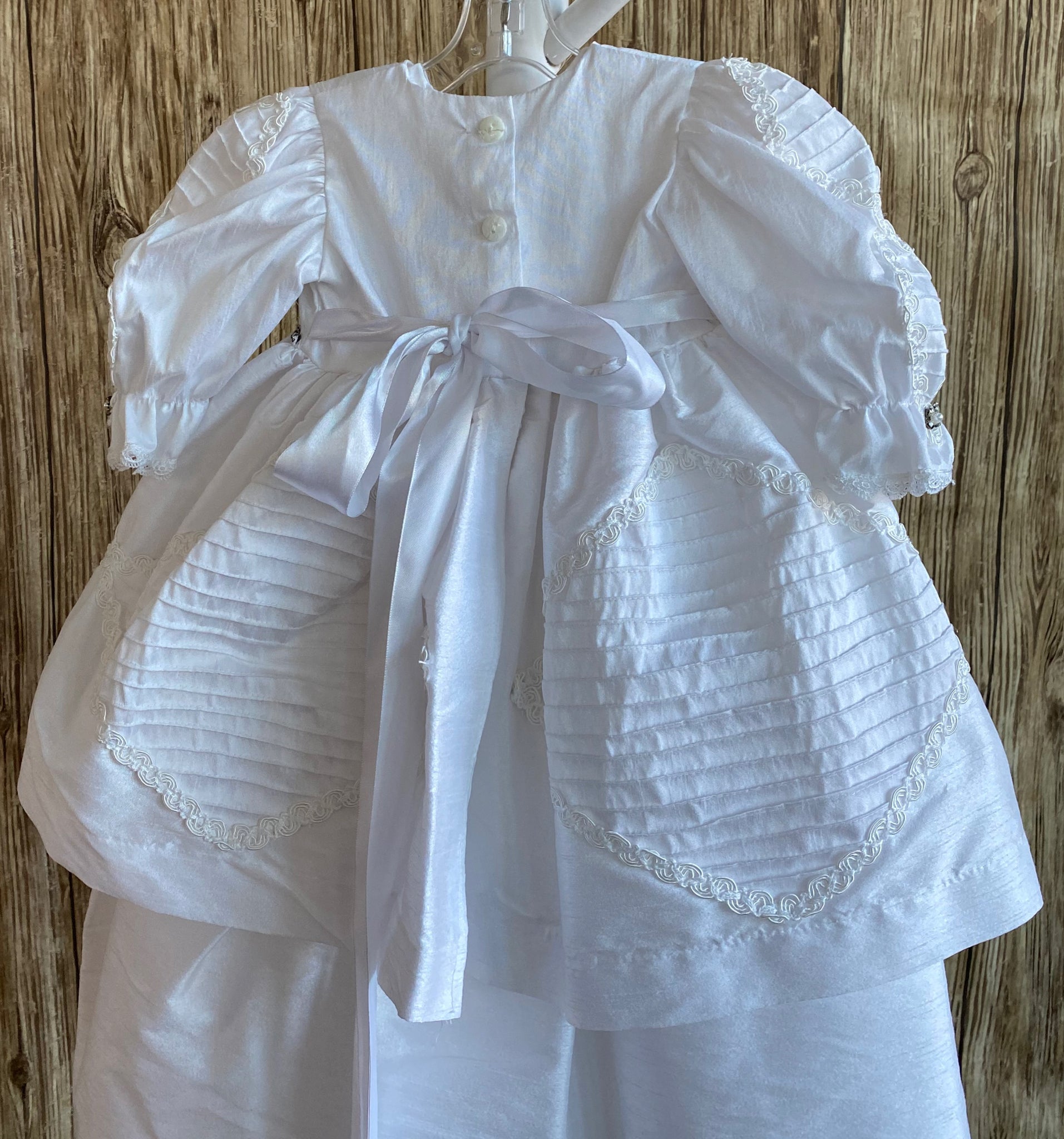 This a beautiful, one-of-a-kind baptism gown.  A lovely gown for a precious child.  White, size 6M Satin bodice Ribbon detailing along bodice and sleeves Rhinestones along bodice  Puffed sleeves Satin skirting with ribbon detailing 