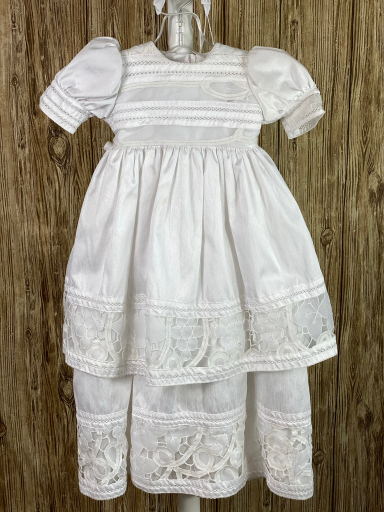 This a beautiful, one-of-a-kind baptism gown.  A lovely gown for a precious child.  White, size 12M Two layered dress Satin bodice with lace detailing Puffed satin sleeves with lace trim Satin skirting with thick lace detailing Satin second layer with thick lace detailing Button closure in the back Lace bonnet with satin ruffled brim