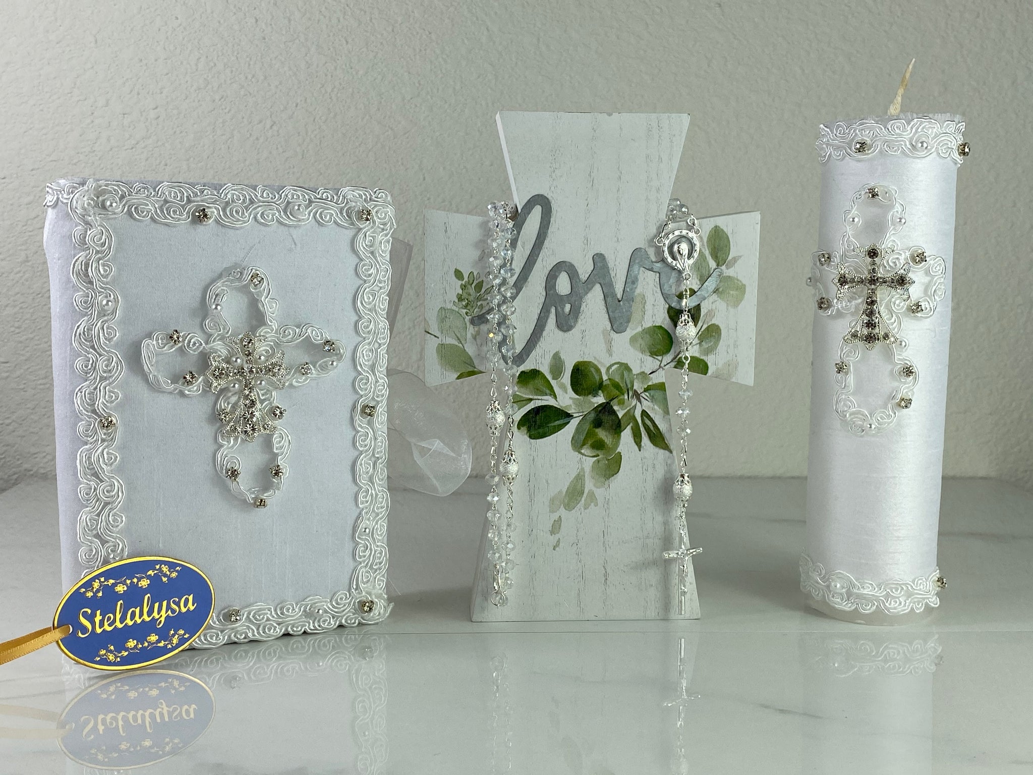 This white Bible Set - candle and bible is handmade and made using satin.  It is elegantly designed with lace, rhinestones, and pearls.  Each piece has a beautiful cross.  The candle is cylinder in shape.  An elegant rosary complements this set.  The rosary is 16.5 in. long and Bible is 6.5 in. by 4.5 in. and the candles approximately the same height.  The Bible includes the Old and New Testament in English. 