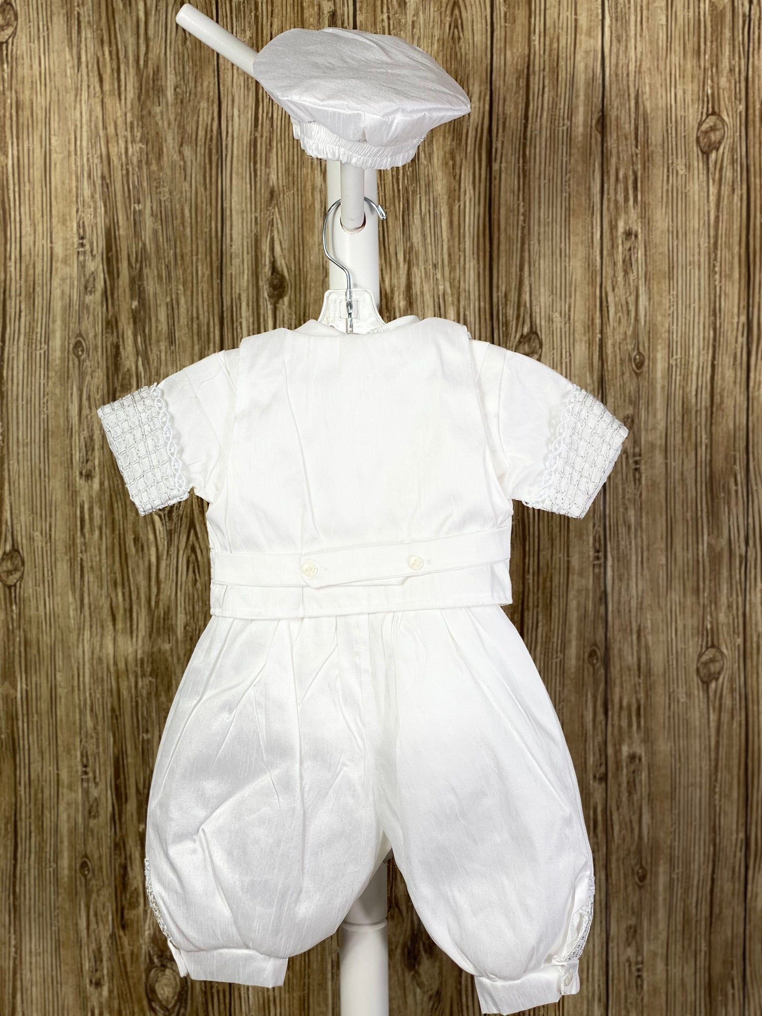 This a beautiful, one-of-a-kind boy’s baptism gown/set.  Lovely clothes for a precious child.  4- piece set including vest, shirt, pants, beret Satin, White pictures shown Grid pattern on vest with embroidered jeweled crosses in checkered pattern Grid pattern on pant legs, cummerbund, shirt bodice, and arm cuffs Intricate trim around cuffs and collar Thin lines around beret trim Tassel pin with 3 rhinestone centered circles