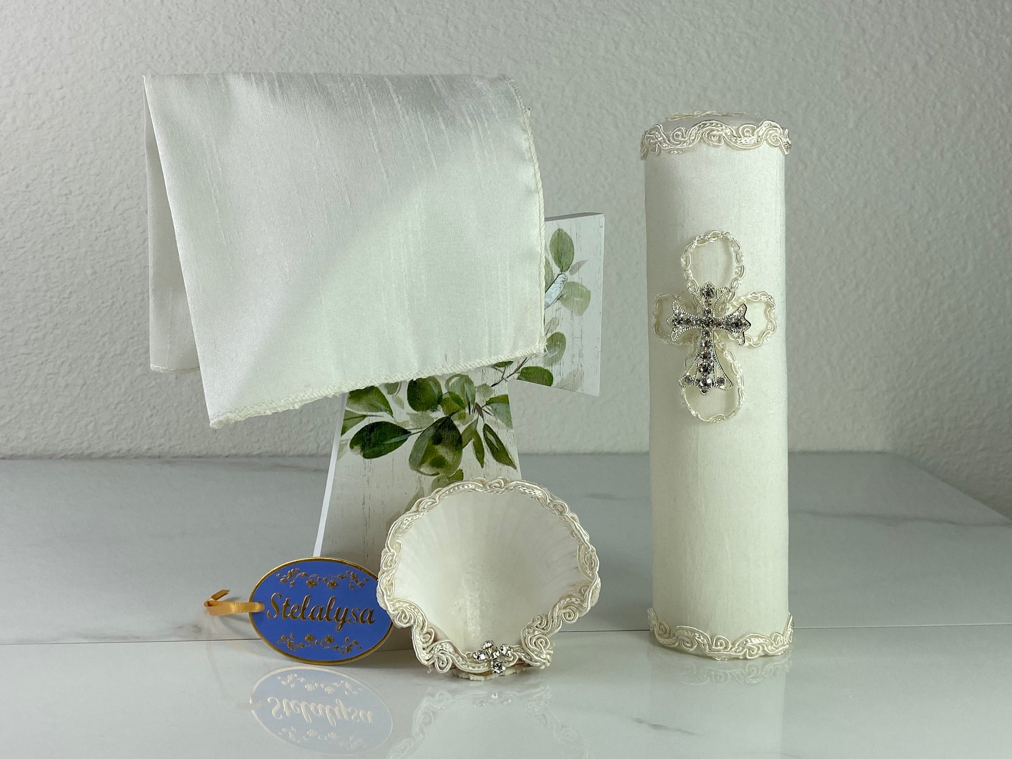 These one-of-a-kind Candle set is handmade and ivory in color.  This candle has a classic look.   It is elegantly decorated with lace and a cross made of crystals making it a gorgeous keepsake.   This candle is cylinder in shape.  To match, the Shell is put together piece by piece to compliment the Candle and Handkerchief.  The Handkerchief is made of satin and embroidered lace to match the Shell and Candle beautifully.  