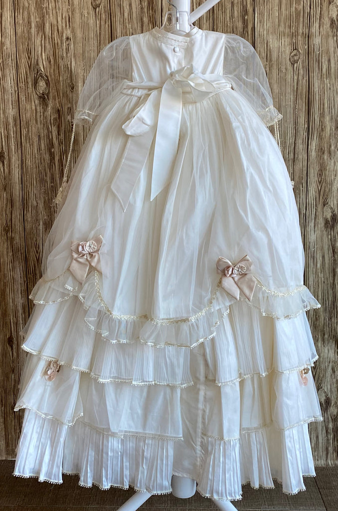 his a beautiful, one-of-a-kind baptism gown.  A lovely gown for a precious child.  Dress, Ivory, size 12M Satin bodice with dusty rose flower detailing Tulle half sleeve Large Champaign bows with flower center Dusty rose and Champaign flower pleats along tulle skirting Champaign bows on edge of skirting with tulle edge Slip  Satin bodice Layer one- thin pleated tulle overlay Layer two- tulle overlay with flowers Layer three- thick pleated tulle overlay