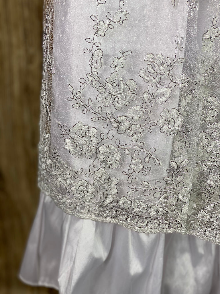 This a beautiful, one-of-a-kind baptism gown.  A lovely gown for a precious child.  White, size 24M Satin bodice with embroidered silver lace overlay Satin puffed sleeves Satin ribbon bow with rhinestone center Satin pleated skirting with embroidered silver lace layer Satin bow in back