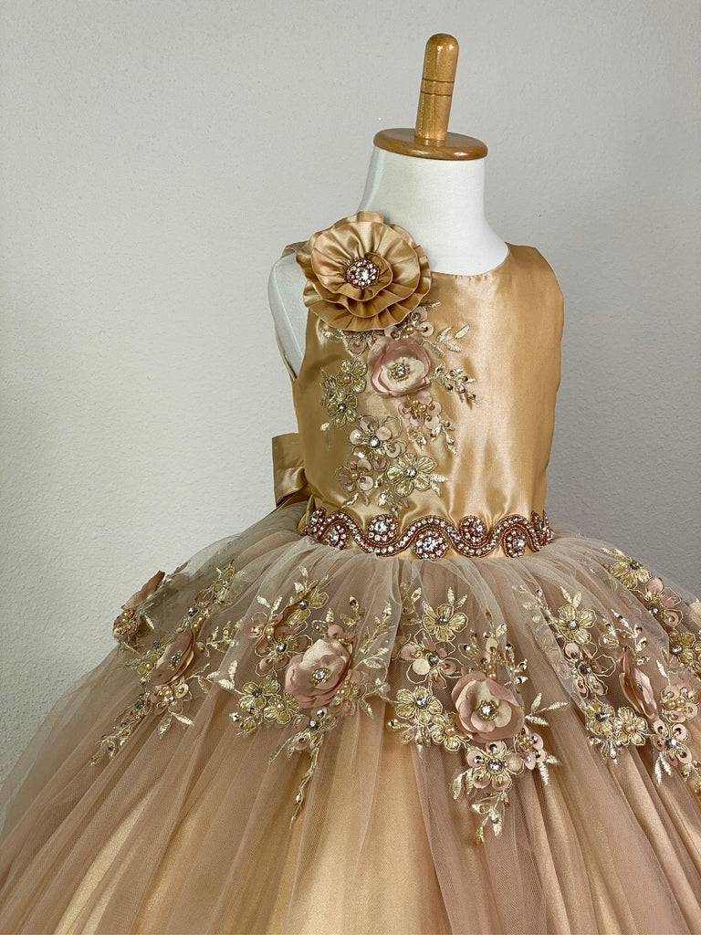 Burgundy, ivory, pink, or champagne scoop neck bodice Large flower placed on right shoulder with rhinestone detailing Embroidered flower applique under large flower Pearl and rhinestone band along lower bodice Satin skirting with tulle overlay Embroidered flower appliques along top of skirt, as well as trimming the edge of skirt Corset backing Burgundy, ivory, pink, or champagne ribbon for large bow Dress pictured with a petticoat