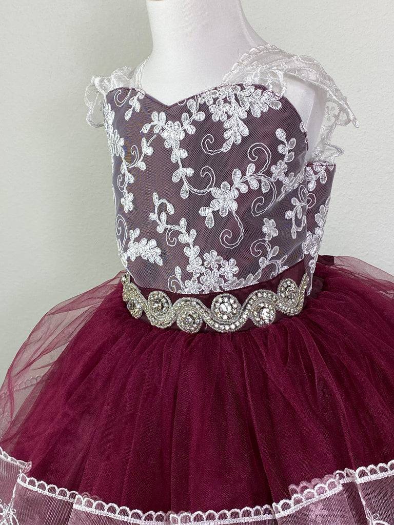 Burgundy, Blush, Sky-blue, or Rose bodice with white embroidered lace overlay Lace strap sleeves Swirled rhinestone blush band along lower bodice Satin and tulle skirting with embroidered ruffled detailing through center Corset back with jeweled eyelets Dress pictured with a petticoat Petticoat not included  Choose from a tulle, cloth, or wire for best look