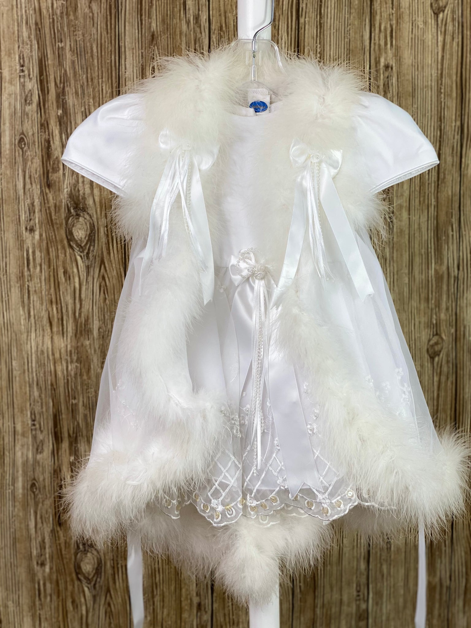 This a beautiful, one-of-a-kind baptism gown.  A lovely gown for a precious child.  White, size 12M Simple satin bodice Satin gathered sleeves Bow in center of bodice Satin skirt with harlequin floral lace Ribbon bow in back Lace vest  Feathered trim on vest Bows on right and left side of vest