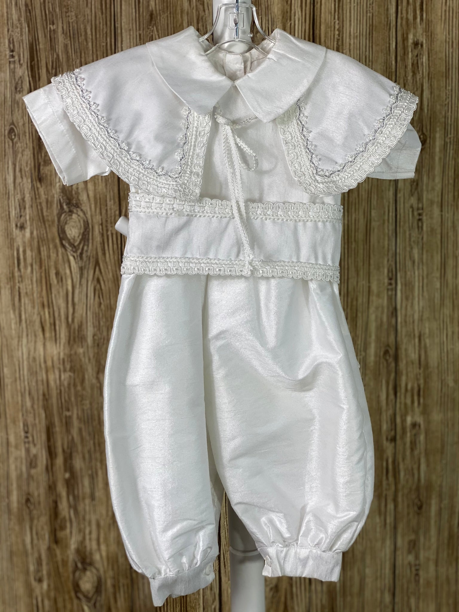 WHITE   4-piece white set including romper, belt, beret and mozzetta Collared with short sleeve Intricate braided trim lining belt and mozzetta edges Thin trim lining cuffs, beret, and bodice Button closure on back Rope closure on mozzetta