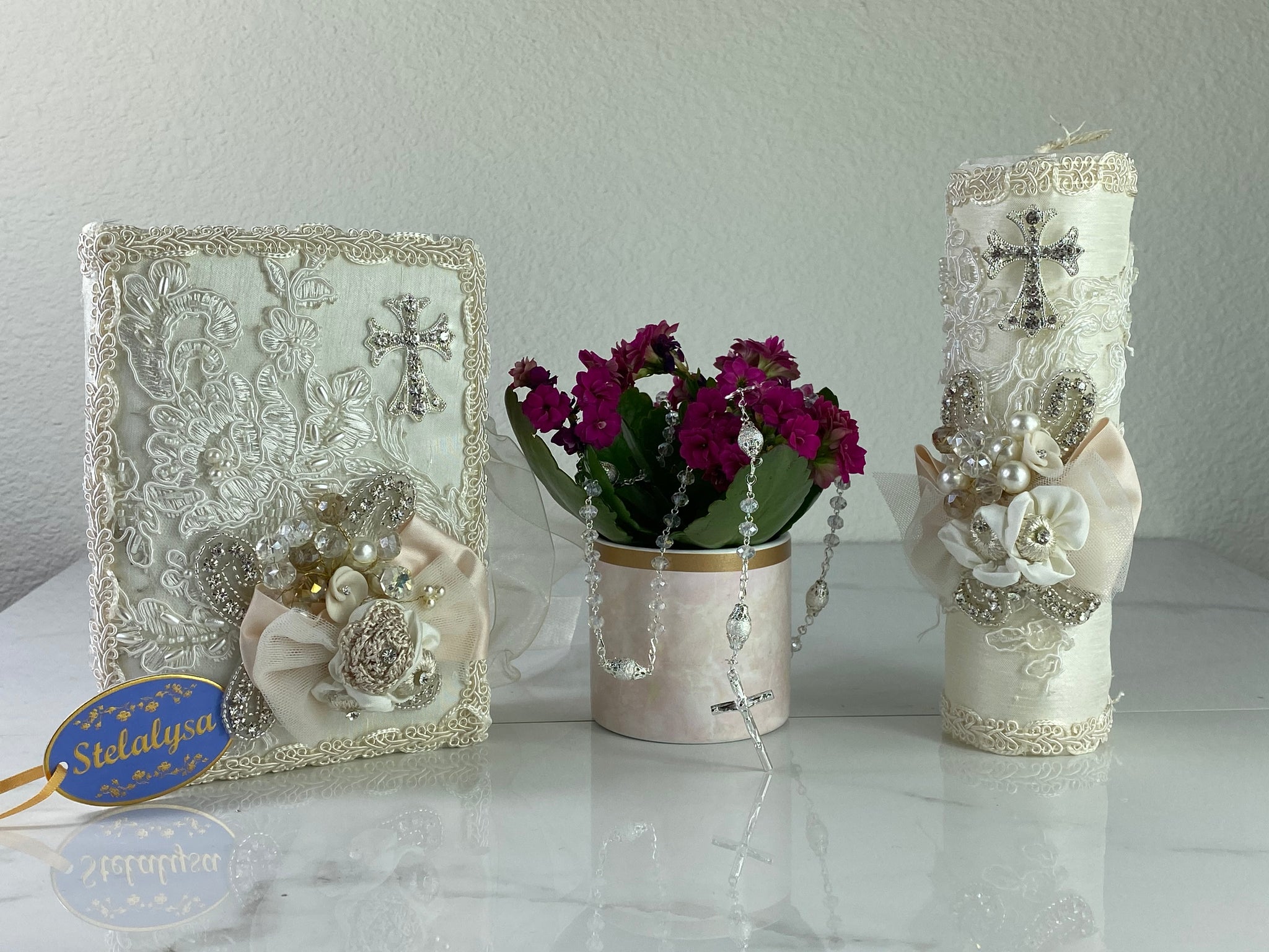 This ivory Bible Set - candle and bible is handmade and made using satin and lace.  It is elegantly designed with pearls, crystals, flowers in different pastel colors, and beads.  Each piece has a beautifully placed cross.  An elegant rosary complements this set.  The rosary is 16.5 in. long and Bible is 6.5 in. by 4.5 in. and the candles approximately the same height.  The Bible includes the Old and New Testament in English. 