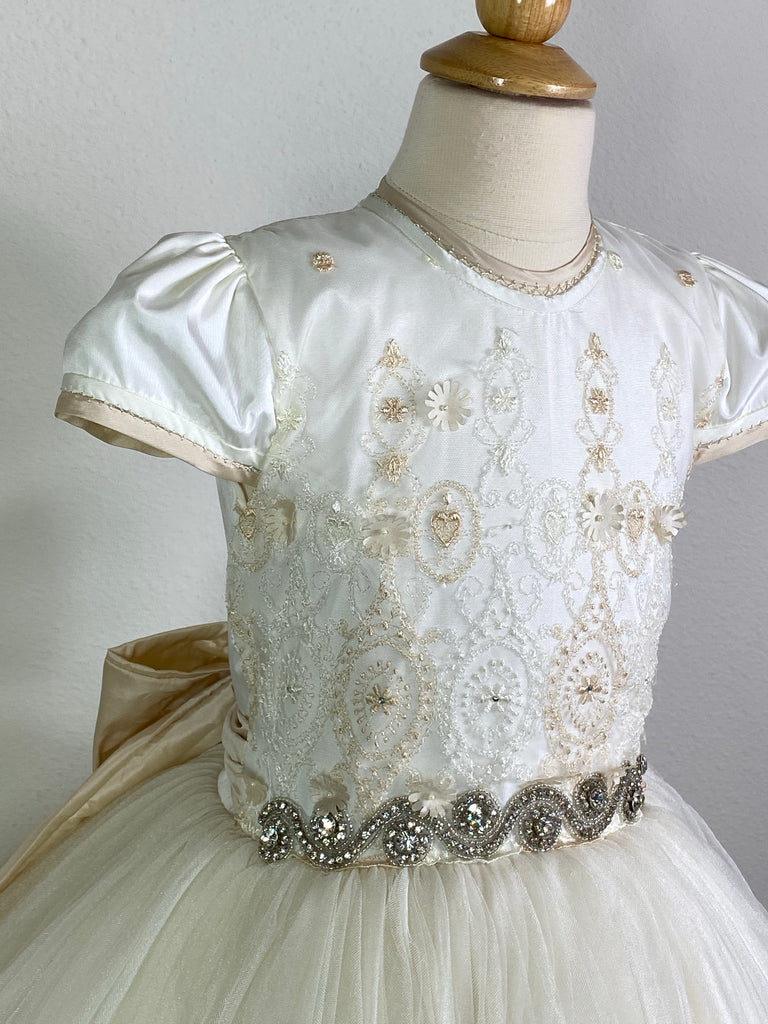 Ivory, size 8 Ivory short sleeve lined with beige trim Ivory and beige embroidered bodice with jewels Swirled rhinestone band around waist Ivory layered tulle skirt Pearl button closure Beige ribbon for large bow