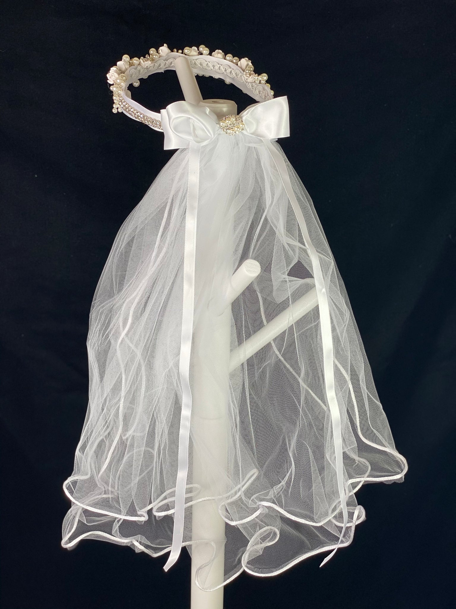 Elegant soft 2 layer tulle veil with delicate hand stitched braided satin trim around the edge and handmade flower halo crown with veil with large white satin bow on back. Ivory roses with rhinestone centers throughout crown band.  Beautiful rhinestone flowers with pearl detailing around crown band.  Rhinestone band around back side of crown.   This double layered veil reaches approximately 24" long, with a crown diameter of 6". Veil has 2" long, 3" wide, comb to secure it in place. 