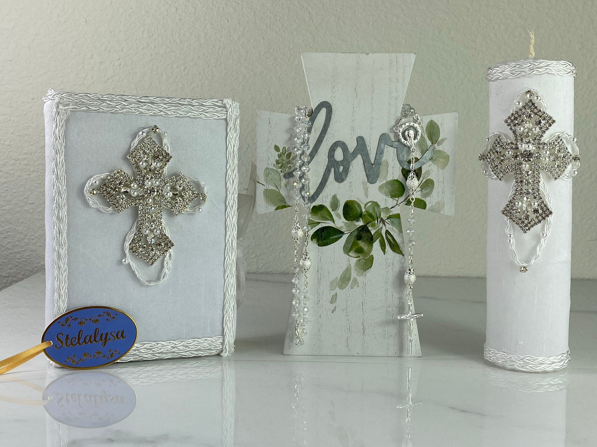 This white Bible Set - candle and bible is handmade and made using satin.  It is elegantly designed with lace, rhinestones, and pearls.  Each piece has a beautiful cross.  The candle is cylinder in shape.  An elegant rosary complements this set.  The rosary is 16.5 in. long and Bible is 6.5 in. by 4.5 in. and the candles approximately the same height.  The Bible includes the Old and New Testament in English. 