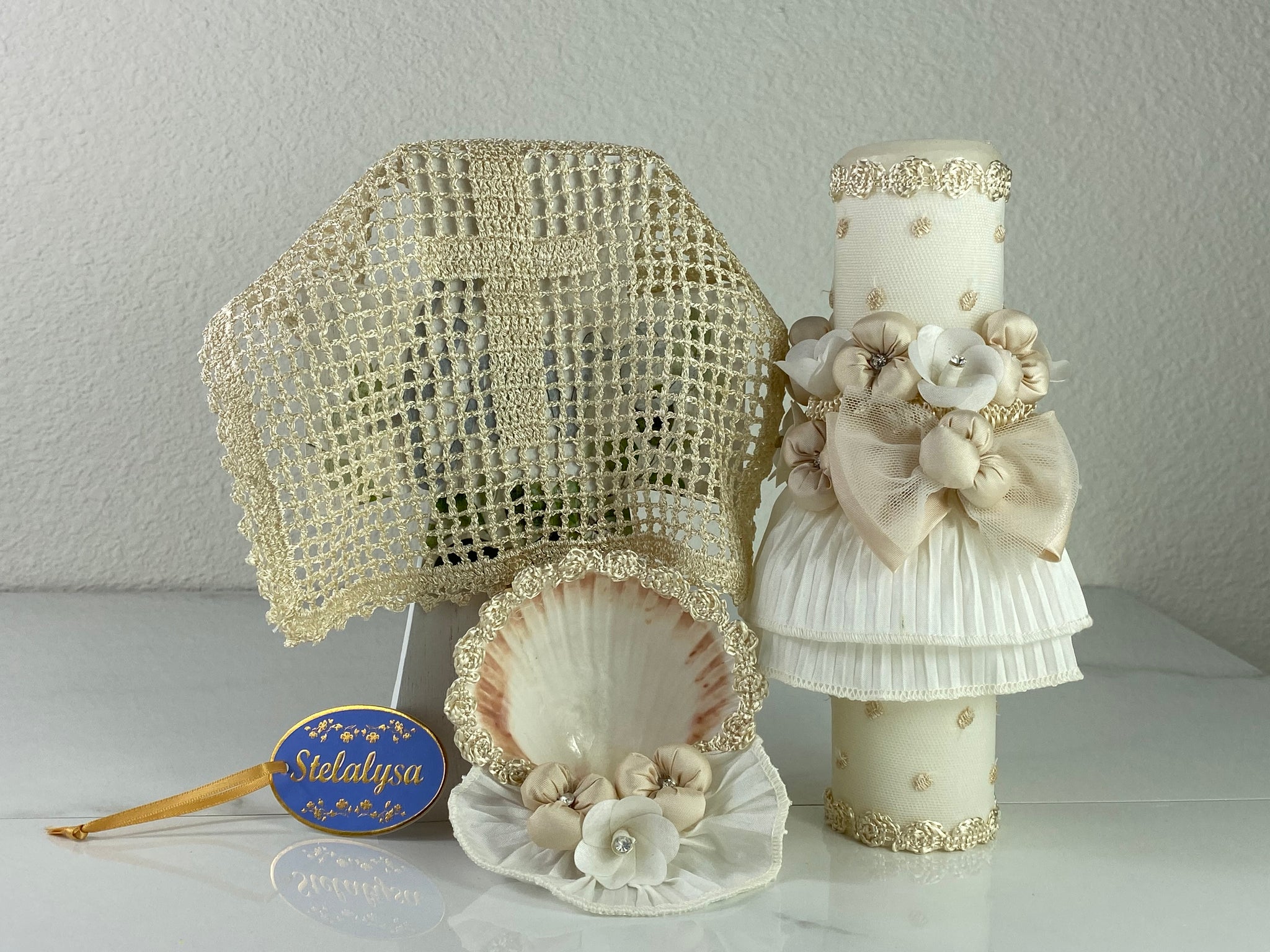 These one-of-a-kind Candle set is handmade and ivory in color.  This candle can also be use with a white baptism outfit because it has an array of light colors including white.   It is uniquely decorated with ribbon, pearls, crystals, flowers, and beads making it a gorgeous keepsake.   This candle is oval in shape.    To match, the Shell is put together piece by piece to compliment the Candle and Handkerchief.  The Handkerchief is elegantly crotchet 
