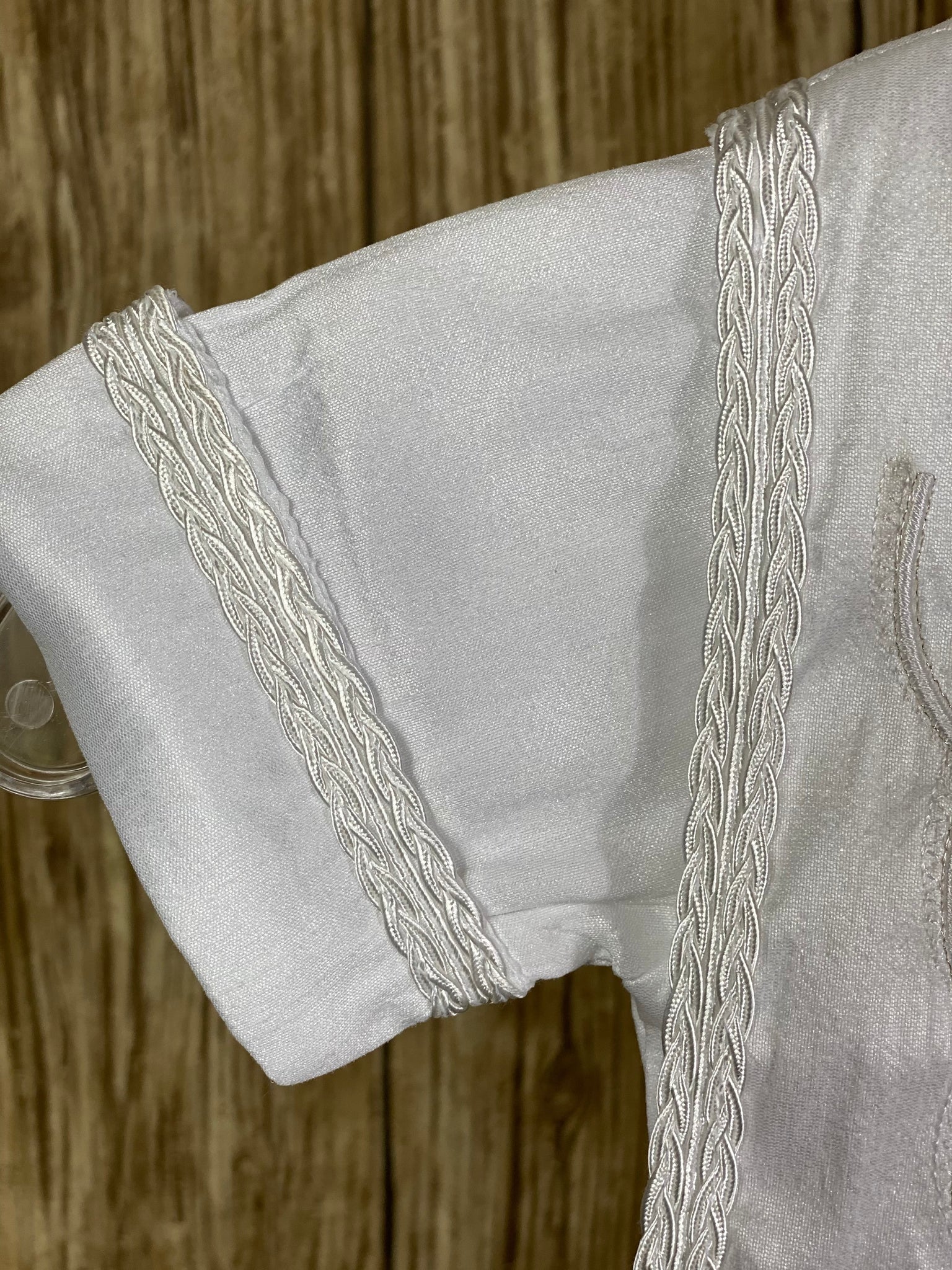 White, size 6M  4-piece set including shirt, pants, stole, beret Collared shirt with short sleeves Embroidered intricate design on stole, trimmed with braided ribbon around edge Ribbon closure on stole Intricate braided trim around beret Braided trim design on cuffs and shirt bodice Buttoning on pant cuffs Elastic banding behind pants Button closure on back of shirt