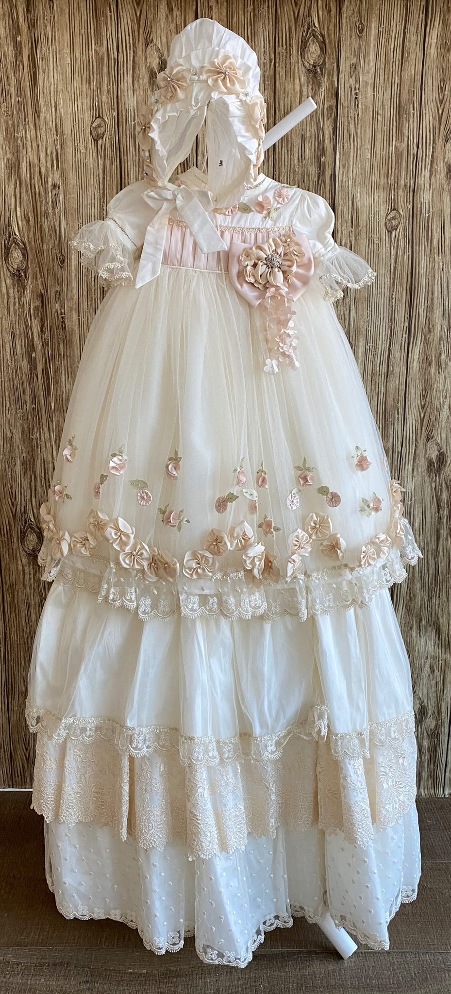This a beautiful, one-of-a-kind baptism gown.  A lovely gown for a precious child.  Dress, Ivory, size 12M Satin bodice with dusty rose pleating  Organza flowers along bodice Satin puff sleeve with tulle brim Large dusty rose bow with Champaign flower center Tulle skirting with leaf detailing Dusty rose flowers along skirting bottom Slip  Satin bodice Layer one- satin with lace trim Layer two- embroidered lace Layer three- satin with dotted mesh overlay 