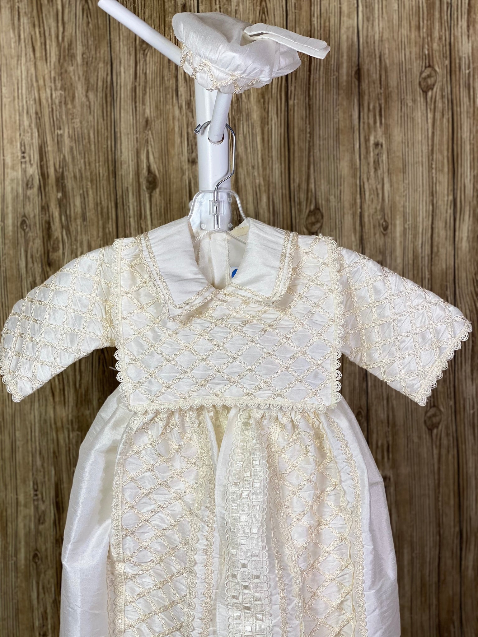 This a beautiful, one-of-a-kind boy’s baptism gown/set.  Lovely clothes for a precious child.  4-piece ivory set including romper, beret, one piece stole, and detachable skirting Diagonal overlapping trim with pearl beading on stole, skirting, and romper Wide embroidered ribbon down skirting Button closure on skirting, inside pant legs, and back of romper Braided layered trim along collar Half sleeve Embroidered scalloped trim around stole and sleeve edge