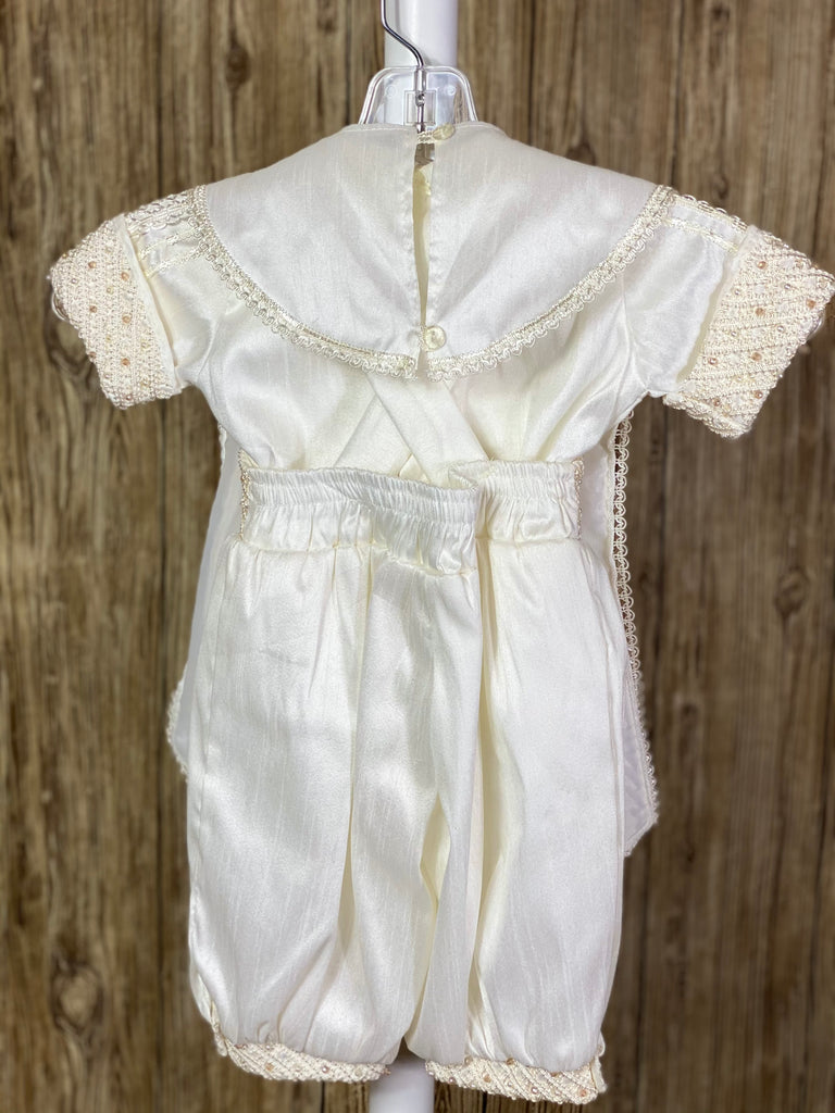 Ivory, size 6M  4-piece set including beret, one piece stole, shirt, suspender pants vertical embroidery covering stole, sleeves, collar, and shirt center Diagonal pin tucking on stole, pant waist and cuffs, beret, and sleeve cuffs Pearls and champagne jewels throughout pin tucking Collared shirt with short sleeves Buttoning on pant cuffs Elastic banding behind pants Button closure on back of shirt Embroidered trim along edge of stole