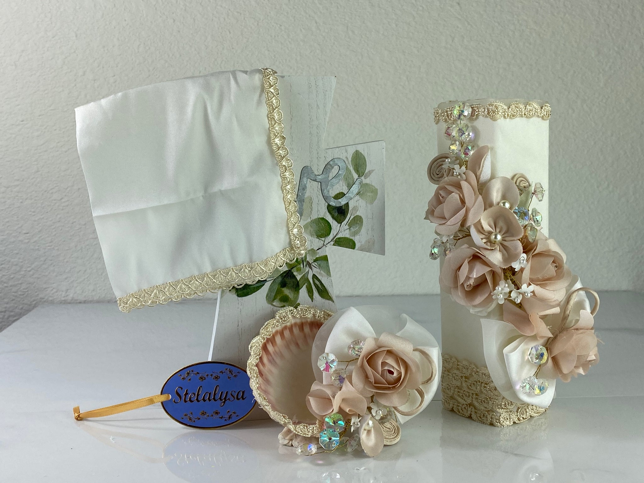 These one-of-a-kind Candle set is handmade and ivory in color.  This candle can also be use with a white baptism outfit because it has an array of light colors including white.   It is uniquely decorated with ribbon, pearls, crystals, flowers, and beads making it a gorgeous keepsake.   This candle is square in shape.    To match, the Shell is put together piece by piece to compliment the Candle and Handkerchief.  The Handkerchief is made of satin and embroidered lace