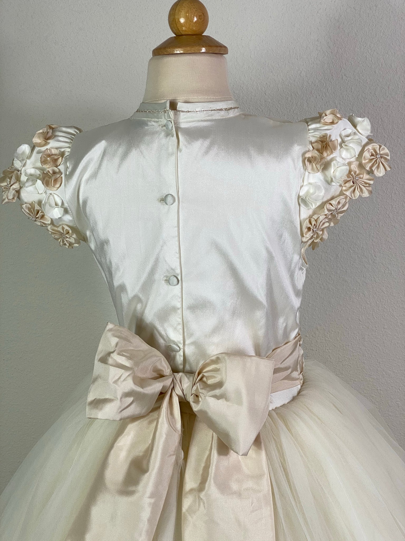 Ivory, size 8 Beige and Ivory floral covered cap sleeve Satin and mesh ivory illusion bodice with flower detailing Beige ruched cummerbund Layered tulle skirt lined with beige satin trim Floral cross detailing below bodice Satin covered button closure Beige ribboning for large bow