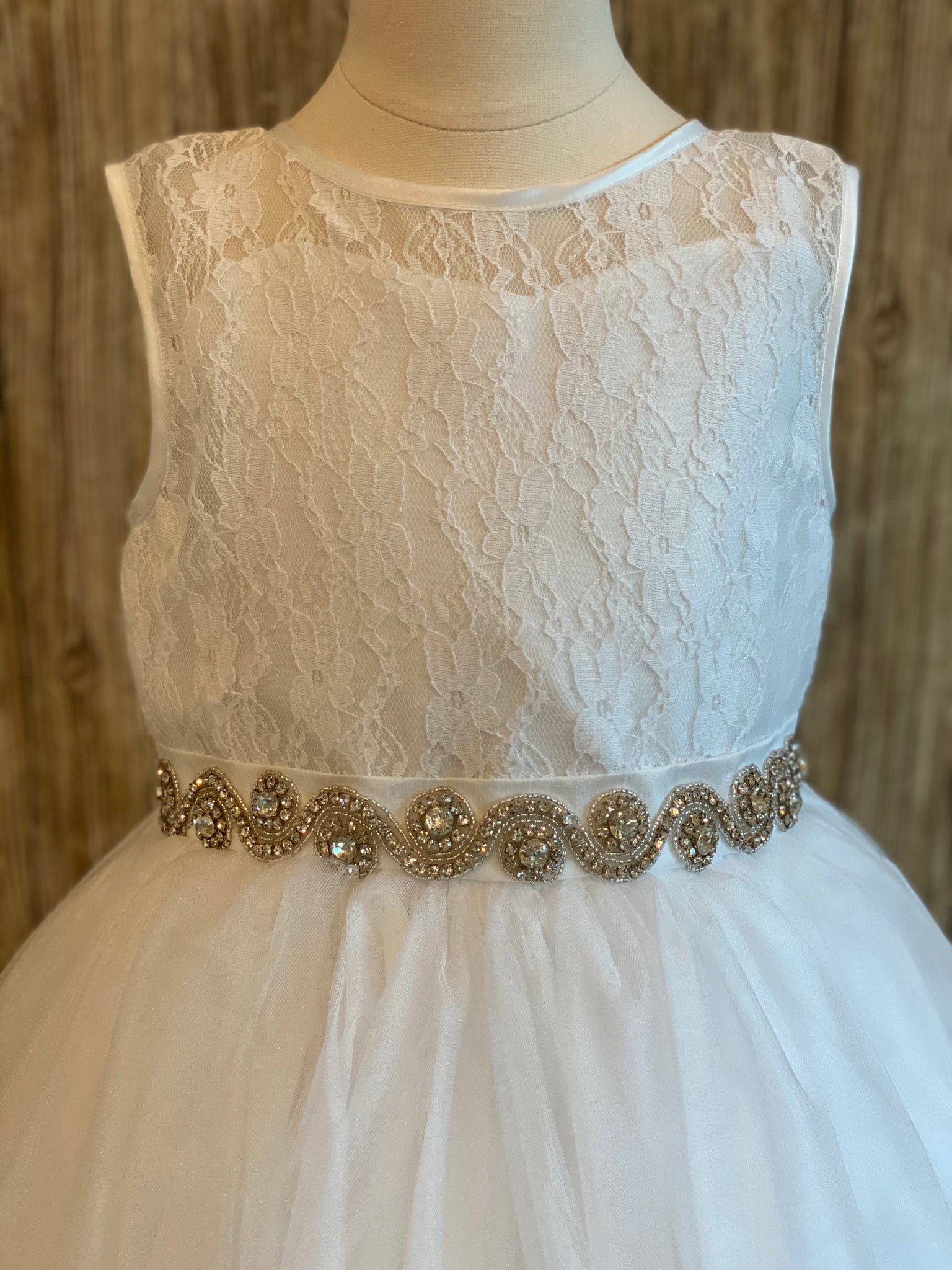 White, size 12 Lace bodice with satin trim Swirled rhinestone belt Tulle skirt Keyhole back Button closure Satin bow