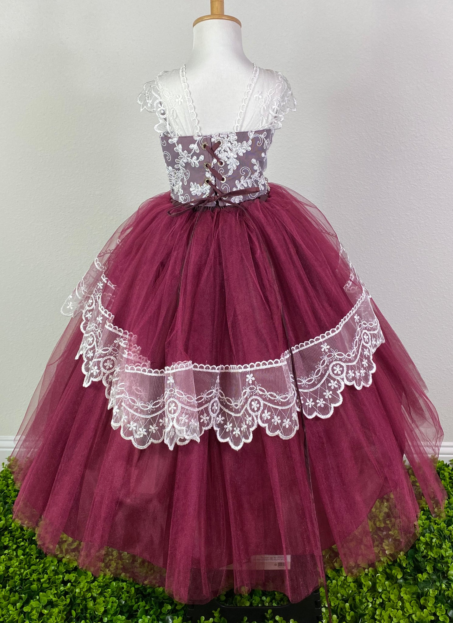Burgundy, Blush, Sky-blue, or Rose bodice with white embroidered lace overlay Lace strap sleeves Swirled rhinestone blush band along lower bodice Satin and tulle skirting with embroidered ruffled detailing through center Corset back with jeweled eyelets Dress pictured with a petticoat Petticoat not included  Choose from a tulle, cloth, or wire for best look