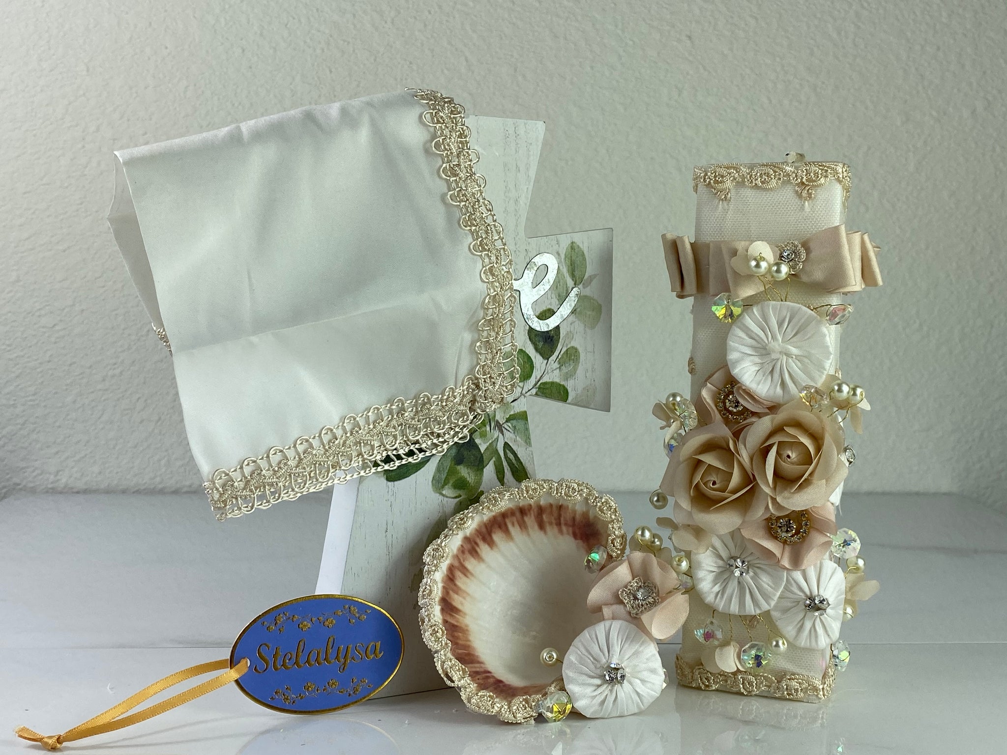 These one-of-a-kind Candle set is handmade and ivory in color.  This candle can also be use with a white baptism outfit because it has an array of light colors including white.   It is uniquely decorated with ribbon, pearls, crystals, flowers, and beads making it a gorgeous keepsake.   This candle is square in shape.    To match, the Shell is put together piece by piece to compliment the Candle and Handkerchief.  