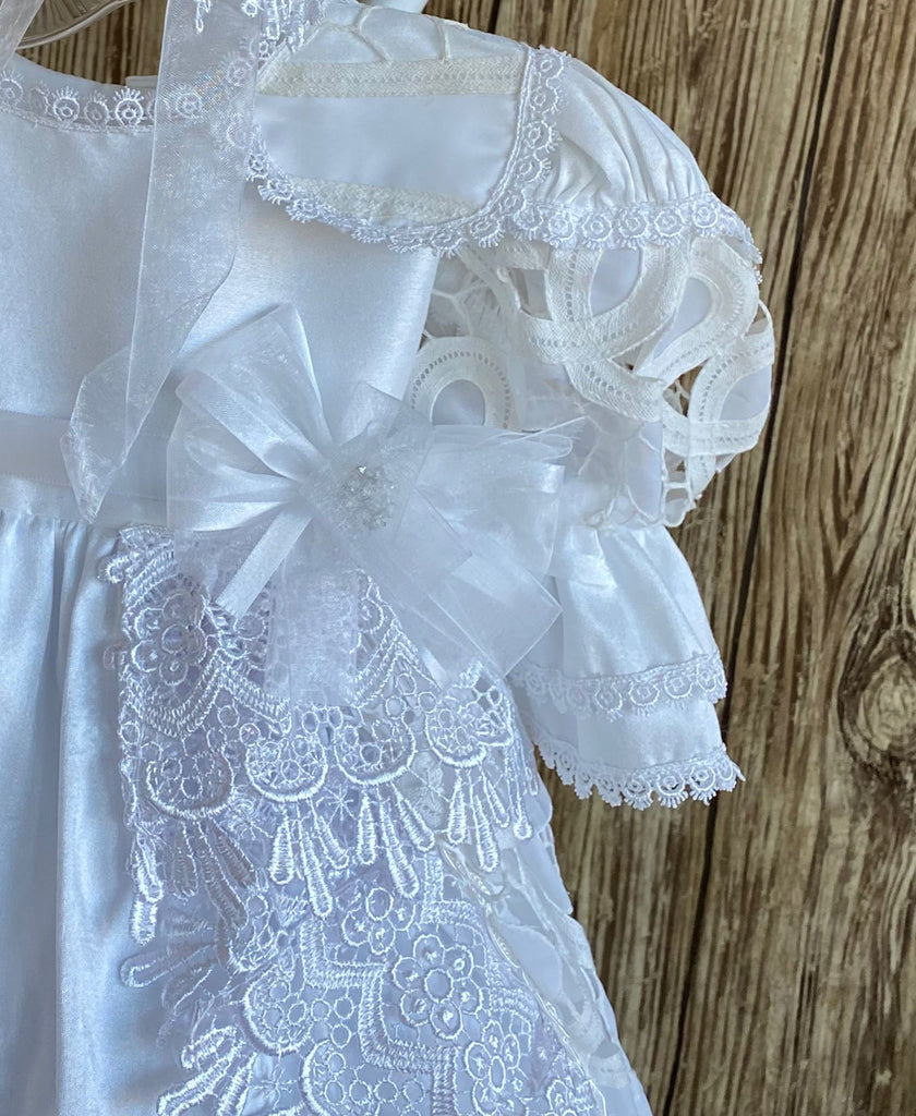 This a beautiful, one-of-a-kind baptism gown.  A lovely gown for a precious child.  White, size 6M Satin bodice with satin collar Beautiful lace trim edging collar and sleeves Gorgeous ribbon flower placed on bodice edge Satin puff sleeve with lace patch  Satin skirting with lace overlay  Thick embroidered lace ribboning around overlay and skirt edge Lovely satin bonnet with thick embroidered lace brim Mesh ribbon closure on bonnet
