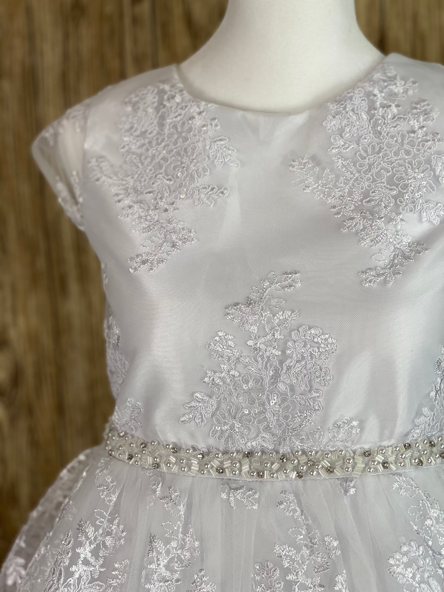 White, size 12 Cap sleeve Scoop neck with embroidered lace bodice Bead, pearl, and rhinestone thin belt Embroidered lace tulle over satin Zipper closure Tulle belt for big bow