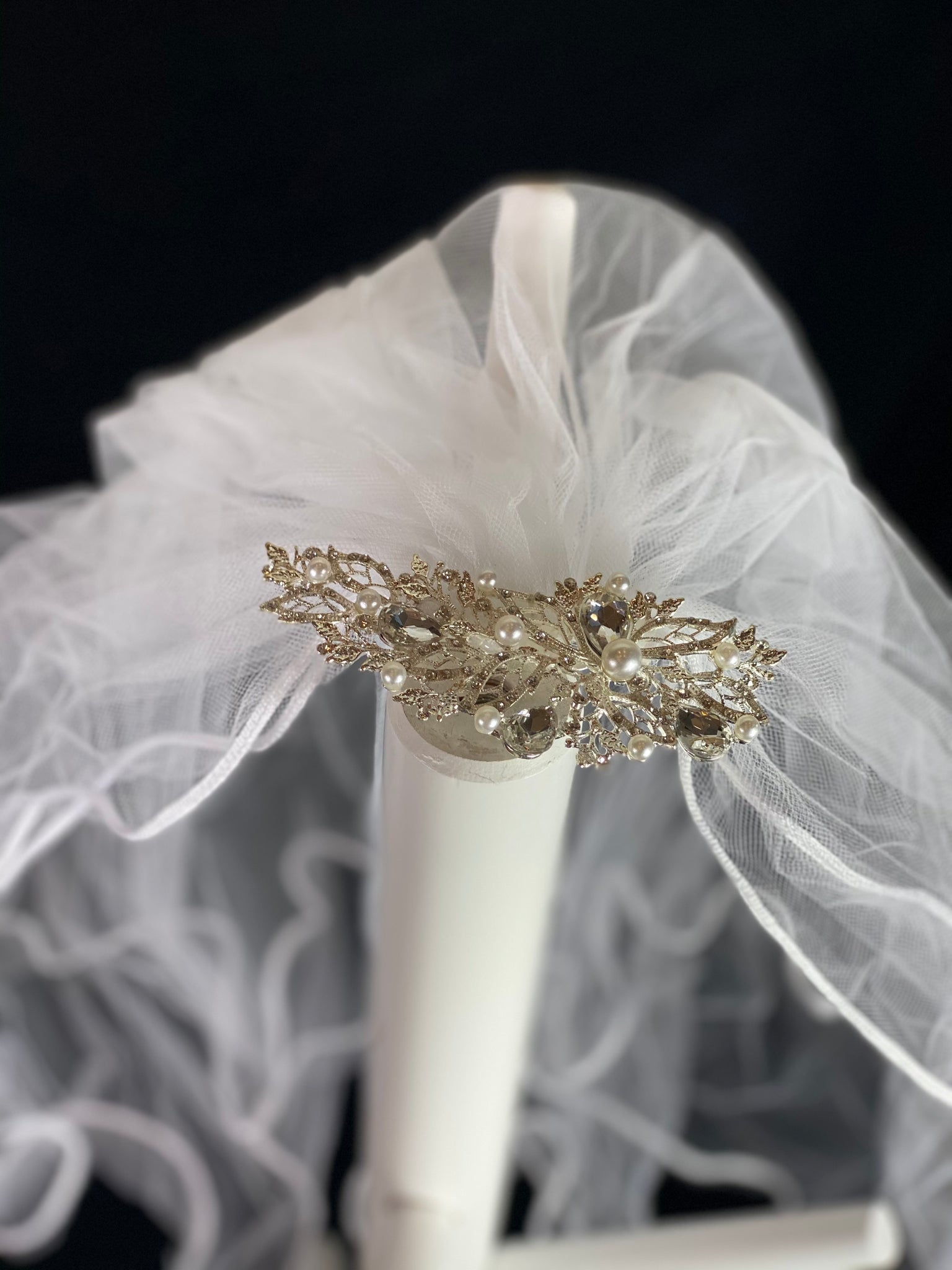 White Elegant First Communion Veil on Decorative Comb with pearls and rhinestones.  Elegant soft 2 layer tulle veil with delicate hand stitched braided satin trim around the edge and handmade decorative comb with pearl and rhinestone detailing.  This double layered veil reaches approximately 21" long. Veil has 1.5" long, 2" wide, metal comb tiara to secure it in place. 