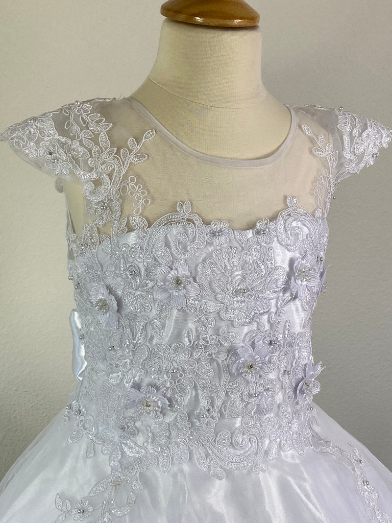 White, size 10 Satin trimmed cap sleeve with scoop neck Floral and lace illusion bodice with pearls and crystals Three-tiered embroidered lace trimmed skirt over satin underlay Zipper closure Satin ribbon for bow Short train