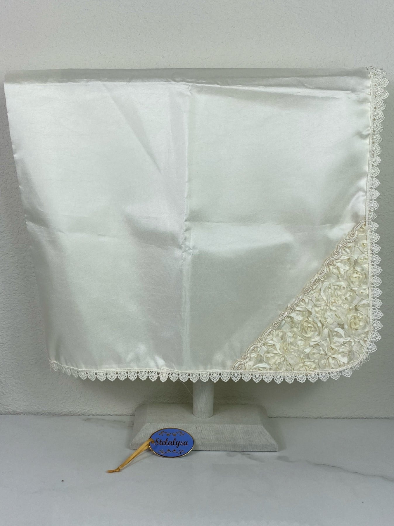 Beautiful ivory silk baptism blanket with embroidered edge and elegant ribbon overlay.
