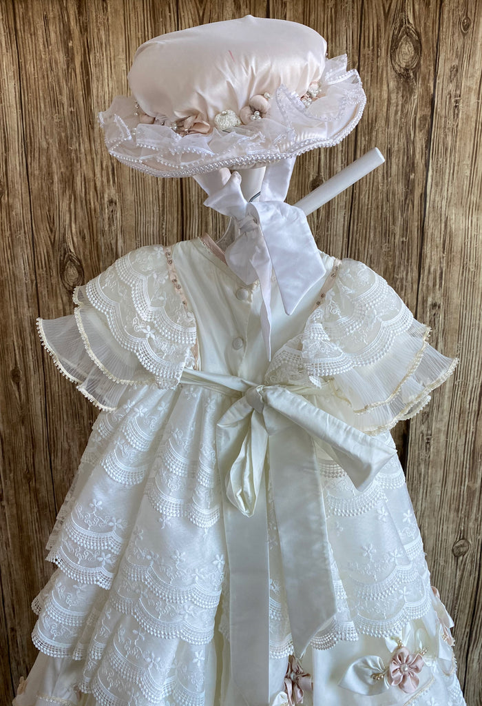 This a beautiful, one-of-a-kind baptism gown.  A lovely gown for a precious child.  Ivory, size 12M Satin bodice with handstitched Champaign flowers Beaded ribboning along bodice/arm edge Multilayered ruffled tulle and crochet lace sleeves Dusty rose flowers belting around bodice Multilayered ruffled tulle and crochet lace skirting around bodice Large bow on skirting Satin dusty rose flowers around layer of skirt  Champaign hat with dusty rose flowers and tulle brim Satin ribbon tie to keep on child's head