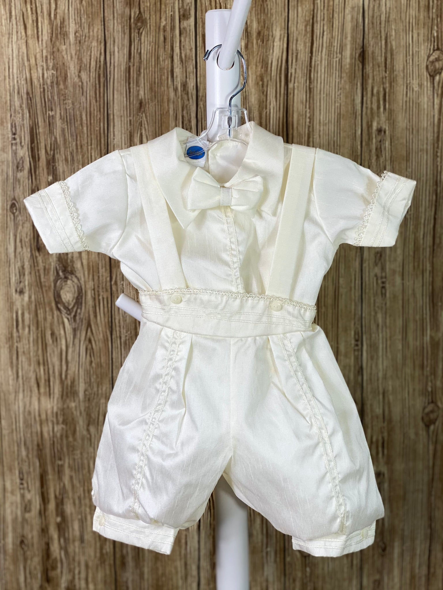This a beautiful, one-of-a-kind boy’s baptism gown/set.  Lovely clothes for a precious child.   IVORY   4-piece white set including beret, vest, shirt, suspender pants JHS symbol embroidered into vest (JHS stands for Jesus Holmium Salvatore, Latin for Jesus Savior of Mankind) Tassel pin with 3 rhinestone centered circles Thin trim along cuffs, beret, and up pant legs Collared shirt with short sleeves Buttoning on pant cuffs Elastic banding behind pants Button closure on back of shirt