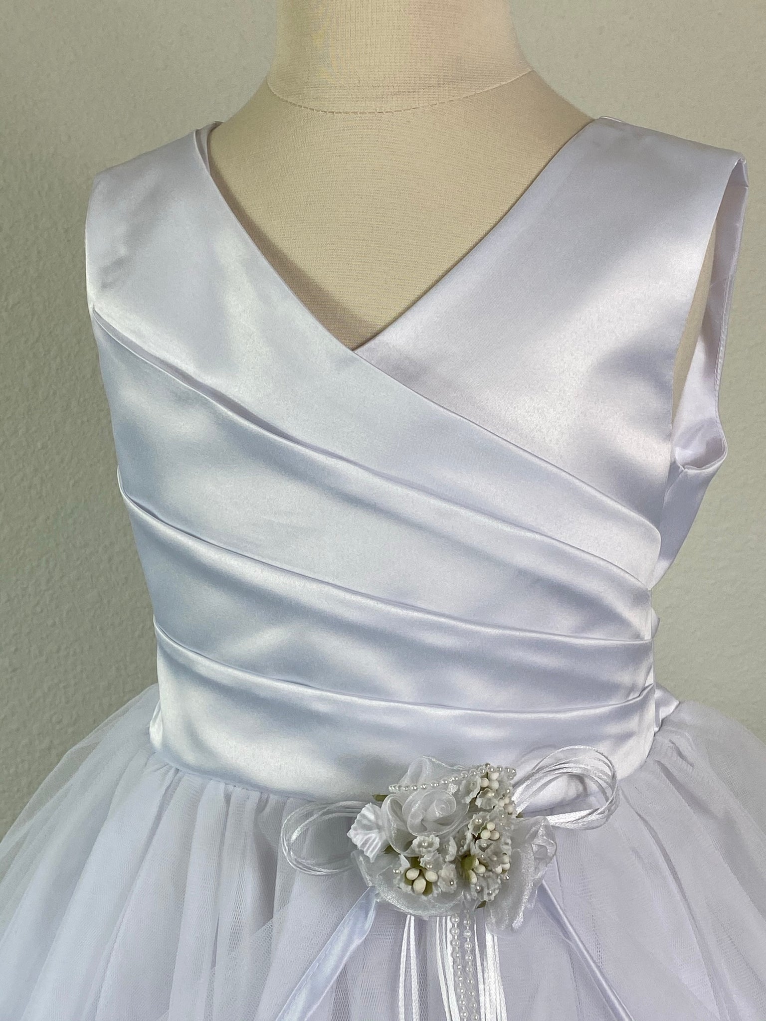 White, size 10 Wrapped Ribbed Bodice Small floral bouquet detailing on lower bodice Gathered mesh cape skirt lined in satin Zipper Closure Satin Ribbon for bow
