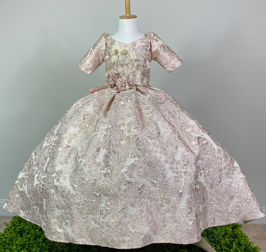 Embossed Champagne or Rose Gold bodice Quarter sleeve Champagne or Rose Gold embroidered applique over bodice Thin rhinestone band around lower bodice Two flowers with rhinestone centers on lower bodice and skirt Pleated embossed skirting Corset back Large bow with rhinestone center on back Dress pictured with a petticoat Petticoat not included  Choose from a tulle, cloth, or wire for best look See Stelalysa's Headbands / Accessories for a matching headband