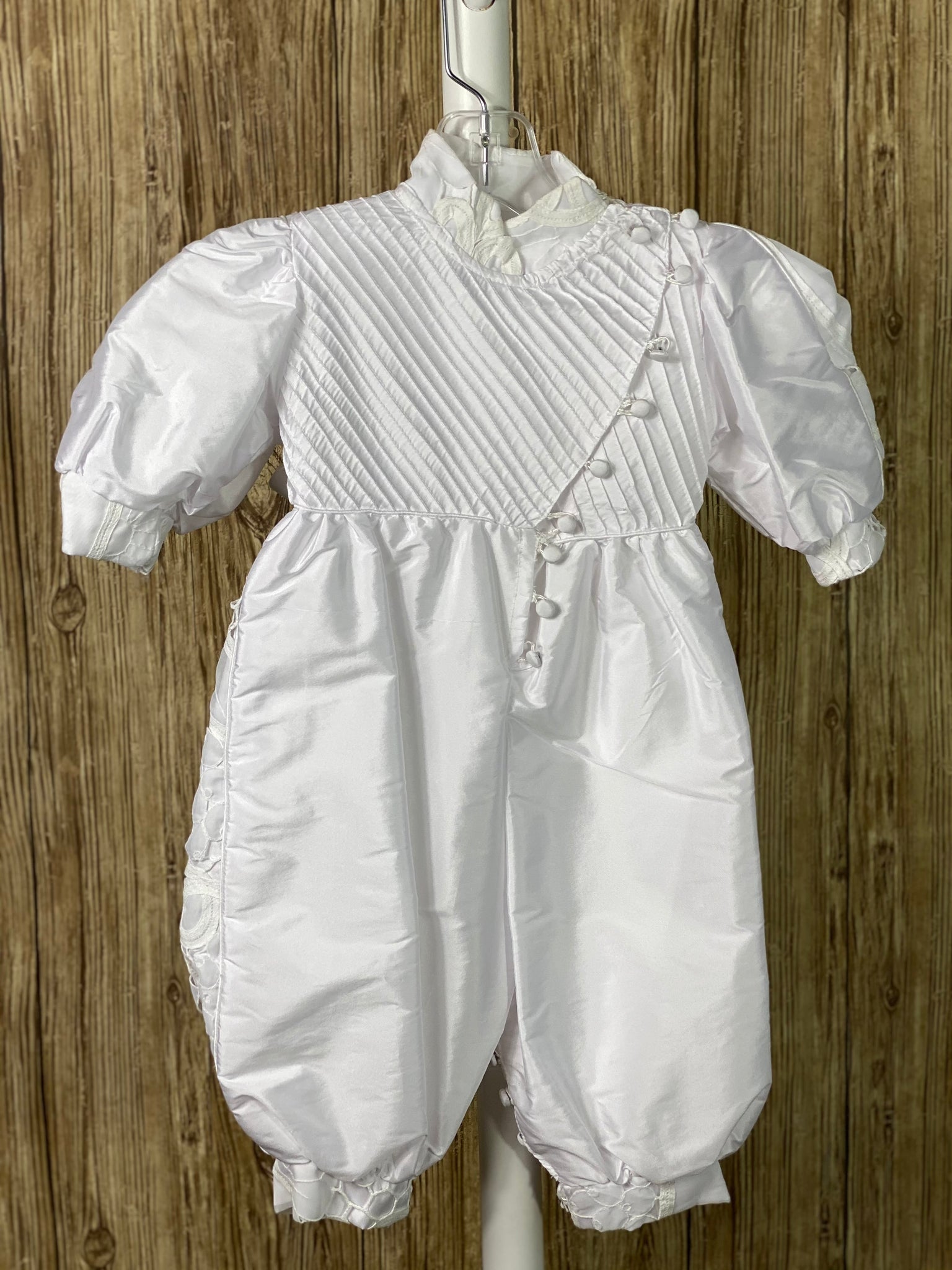 White, size 12M 3-piece set including romper, cape, beret Collared shirt with long sleeves Button closure on cape Wide embroidered lace edging on beret edge, cape and collar edges, and romper cuffs Pin striping on top romper bodice Elastic banding on back of pants Button closure on front of shirt and inside seam of legs