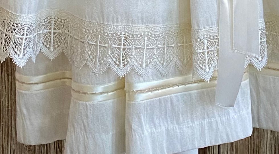 This a beautiful, one-of-a-kind baptism gown.  A lovely gown for a precious child.  Ivory, size 12M Satin bodice with hand embroidered floral design Handstitched layered cap sleeve Layered satin skirting with hemstitching between each layer Embroidered lace band around bottom layer  Long satin ribbon for bow