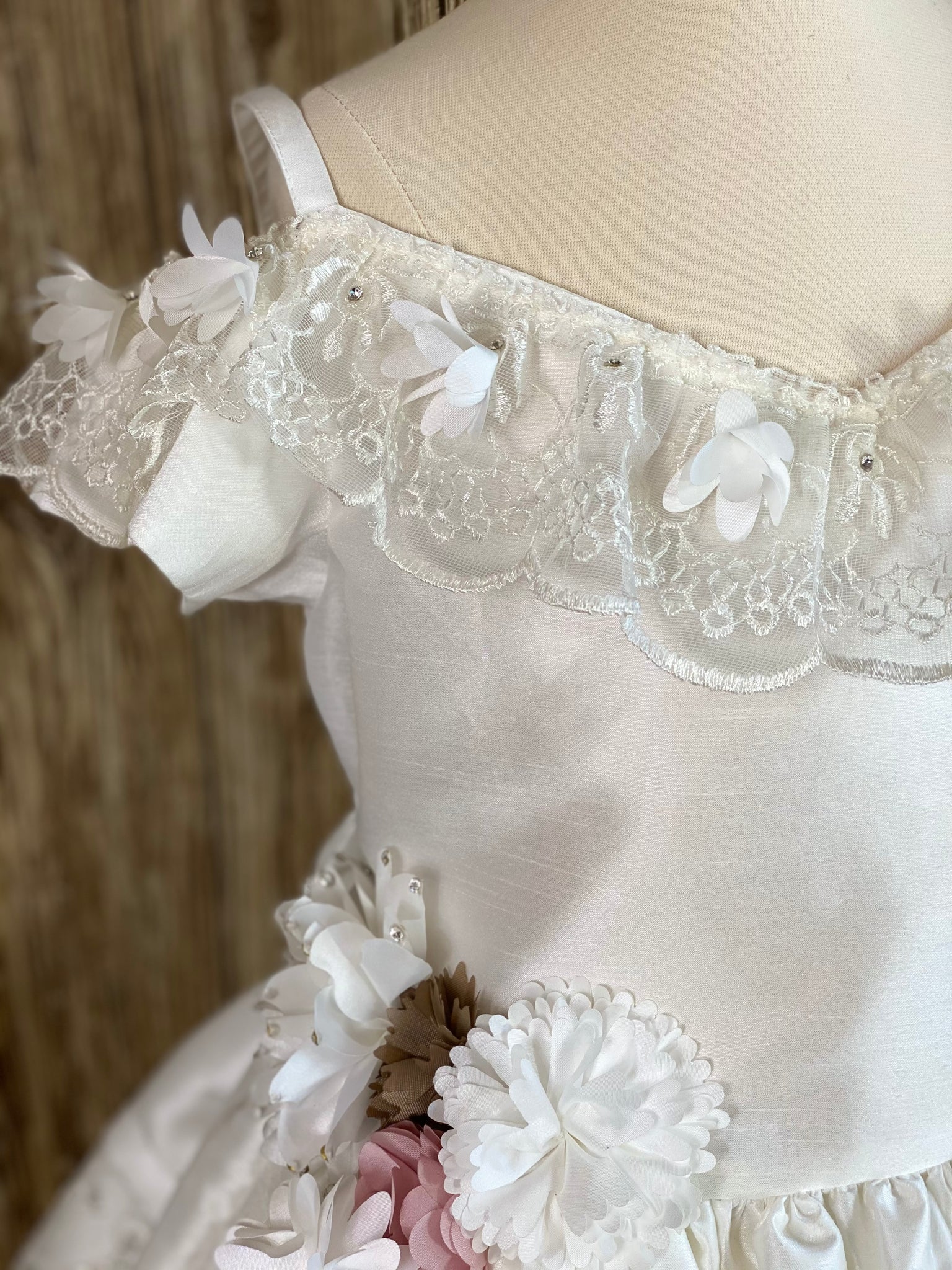 Ivory, size 10 Off the shoulder Laced trimmed along top of satin bodice Flower detailing around right side of bodice leading to skirt Gorgeous lace paneling along skirt Dress comes with detachable skirt to make dress short or long Button closure Big satin bow on back