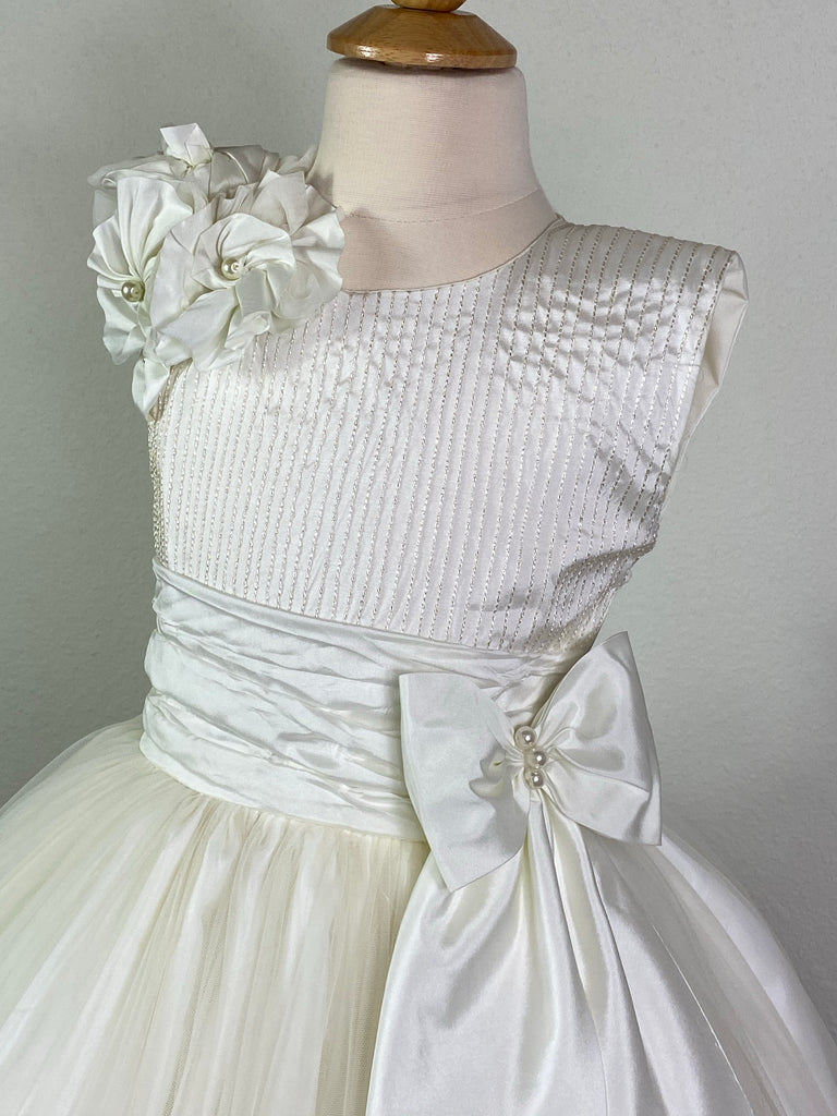 Ivory, size 10 Embroidered pinstripe bodice with ivory satin flowers on shoulder Large bow with pearl center on ivory ruched cummerbund Layered tulle skirt with large pinwheel flowers and braided stripes along edge Satin covered button closure Ivory ribbon for large bow