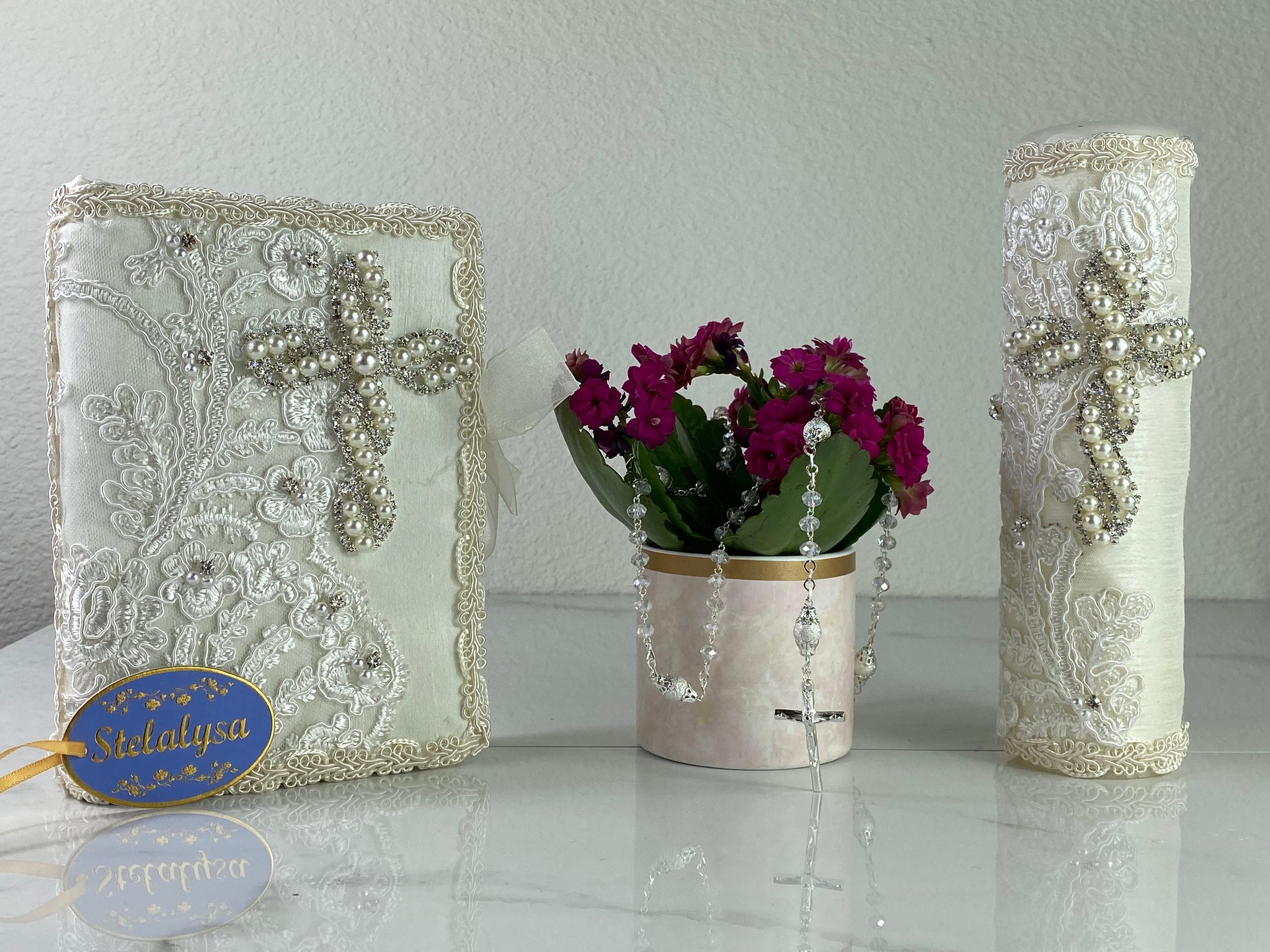 This ivory Bible Set - candle and bible is handmade and made using satin and lace.  It is elegantly designed with lots of gorgeous pearls, crystals, and embroidered lace.  Each piece has a beautiful cross.  An elegant rosary complements this set.  The rosary is 16.5 in. long and Bible is 6.5 in. by 4.5 in. and the candles approximately the same height.  The Bible includes the Old and New Testament in English. 