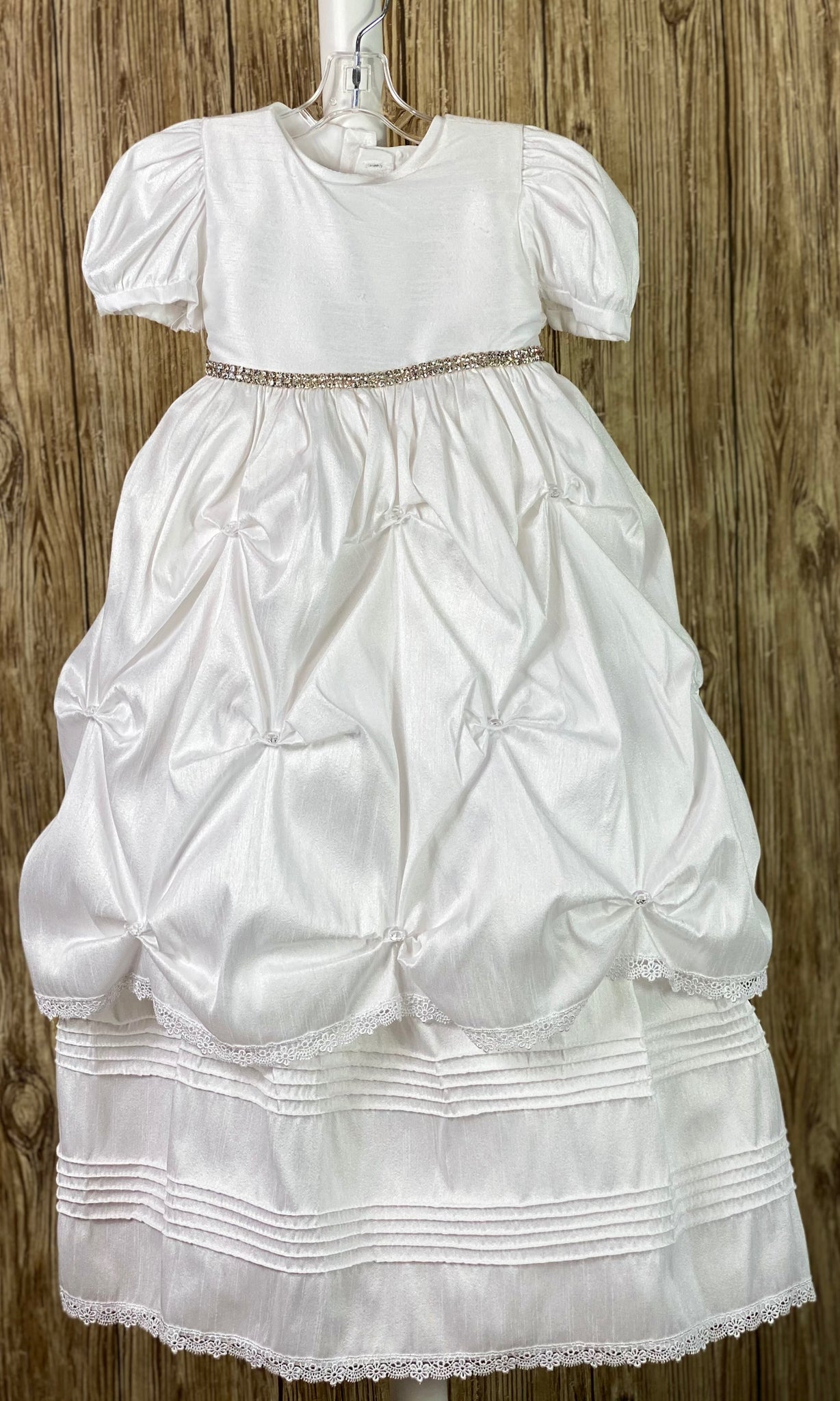 This a beautiful, one-of-a-kind baptism gown.  A lovely gown for a precious child.  White, size 24M Two layer dress Satin bodice  Rhinestone belting Puffed satin sleeves Gathered ruffled skirting with rhinestones Second layer has horizonal pinstripes with lace trim  Satin bow in back