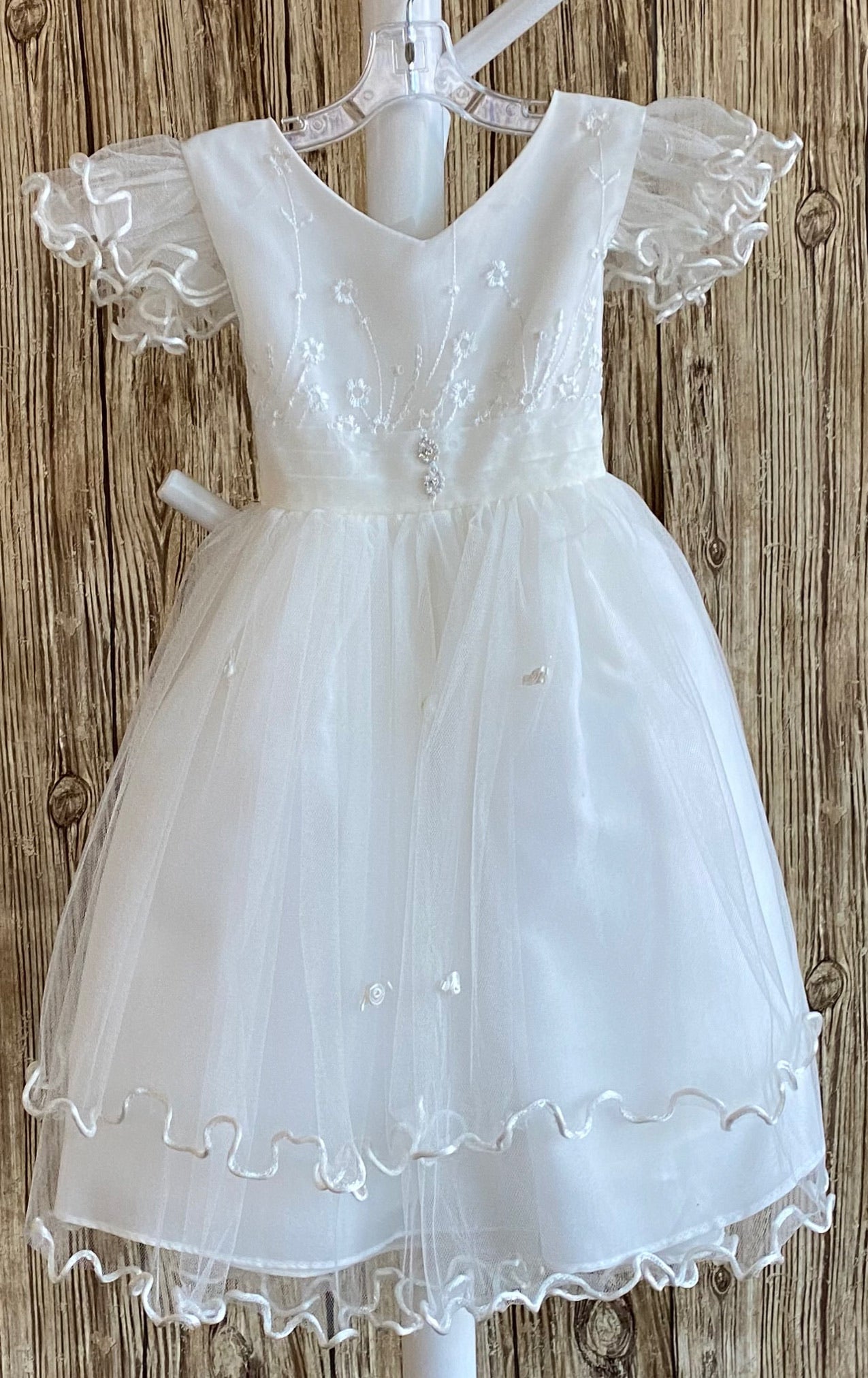 This a beautiful, one-of-a-kind baptism gown.  A lovely gown for a precious child.  White, size 12M Lettuce edge tulle sleeves Satin V-neck bodice with embroidered flowers 2 rhinestone flowers placed on middle of bodice edge Lace skirting with lettuce edge Roses placed throughout skirting 