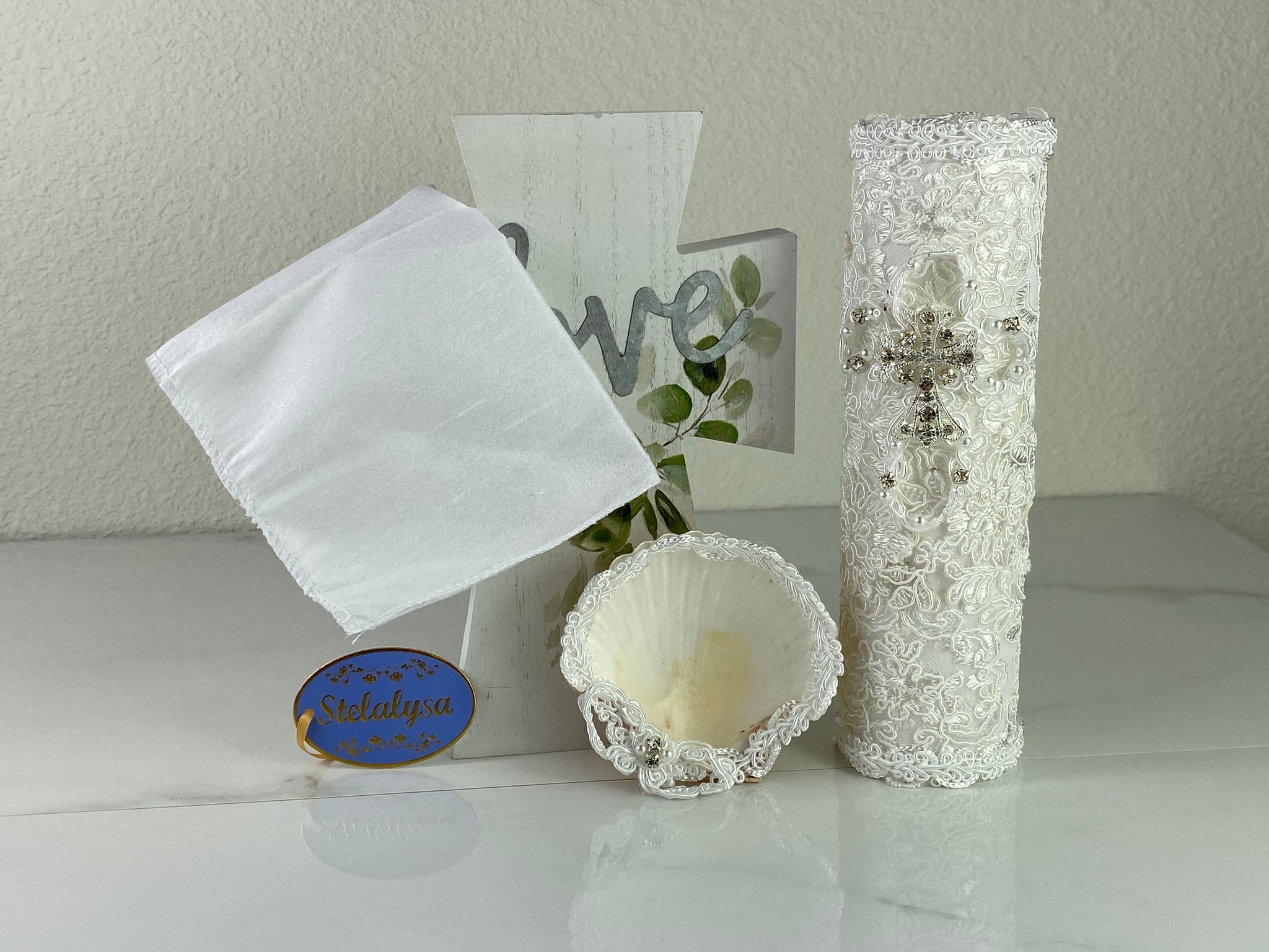 These one-of-a-kind Candle set is handmade and white in color.  This candle has a classic look.   It is uniquely decorated with crystals, lace, and cross making it a gorgeous keepsake.   This candle is cylinder in shape.    To match, the Shell is put together piece by piece to compliment the Candle and Handkerchief.  The Handkerchief is made of satin and embroidered lace to match the Shell and Candle beautifully.  