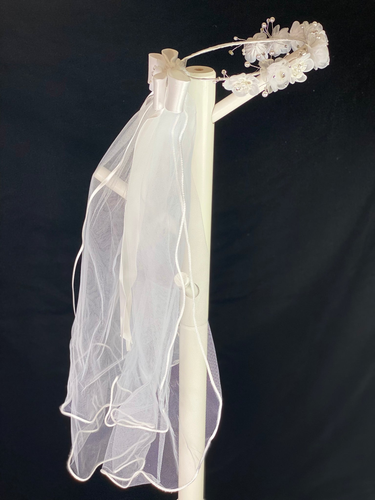 Elegant soft 2 layer tulle veil with delicate hand stitched braided satin trim around the edge and handmade flower halo crown with veil with large white satin bow on back. Organza flowers with sparkling rhinestone petals and centers. Beautiful pearl leaves sticking out around flowers.  This double layered veil reaches approximately 24" long, with a crown diameter of 6". Veil has 2" long, 3" wide, comb to secure it in place. 