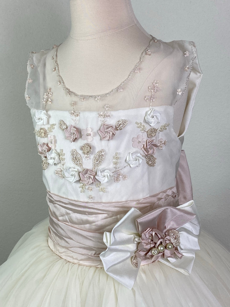 Ivory, size 10 Hand-stitched edging along arm holes and neckline Antique Rose and Ivory floral detailing with pearl center Antique Rose ruched cummerbund with pearl detailing in large bow Tulle skirt with antique rose satin trim Satin covered button closure Antique Rose ribboning for large bow Antique Rose satin trim