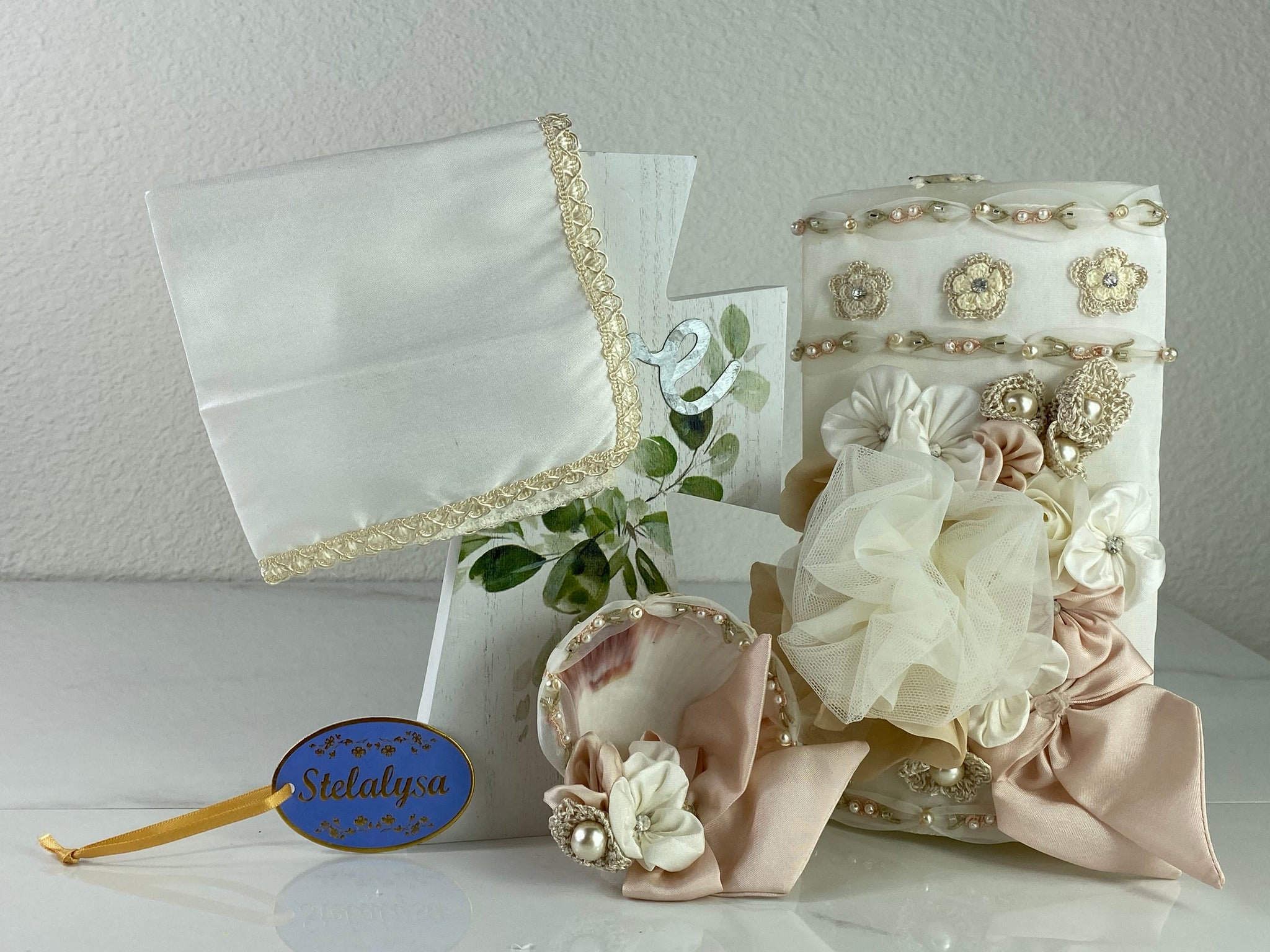 These one-of-a-kind Candle set is handmade and ivory in color.  This candle can also be use with a white baptism outfit because it has an array of light colors including white.   It is uniquely decorated with crochet and satin flowers, ribbon, pearls, crystals, and beads making it a gorgeous keepsake.   This candle is oval in shape.    To match, the Shell is put together piece by piece to compliment the Candle and Handkerchief.  The Handkerchief is made of satin and embroidered lace