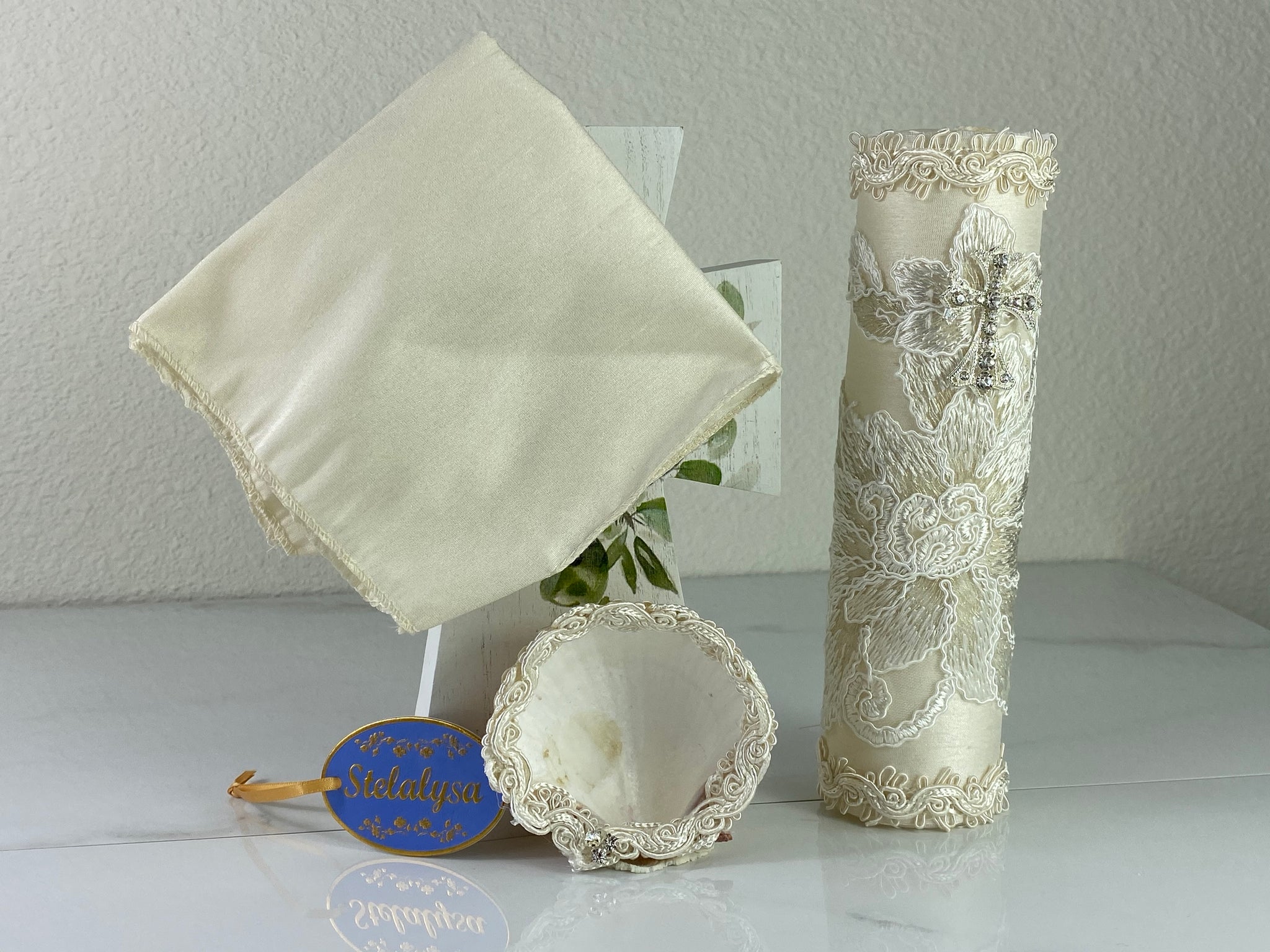 These one-of-a-kind Candle set is handmade and ivory in color.  This candle has a beautiful classic look.   It is beautifully wrapped in lace with a cross with crystals making it a gorgeous keepsake.   This candle is cylinder in shape.  To match, the shell is put together piece by piece to compliment the Candle and Handkerchief.  The Handkerchief is made of satin and embroidered lace to match the Shell and Candle beautifully.  