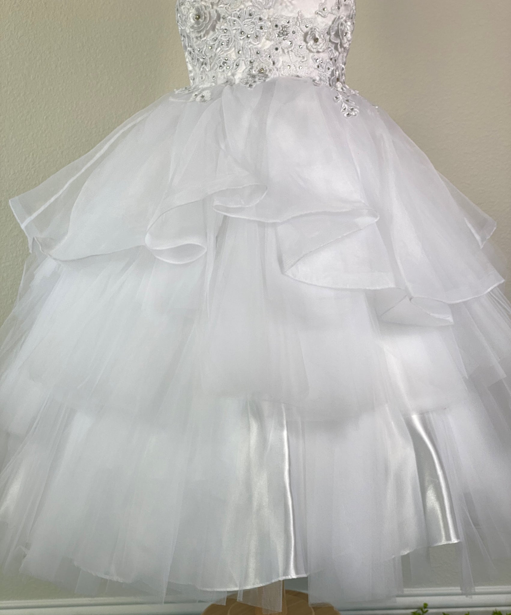 White, size 8 Embroidered Tulle over satin bodice with flowers and crystals throughout Layered ruffled mesh skirt over satin underlay Zipper closure Satin ribbon for bow