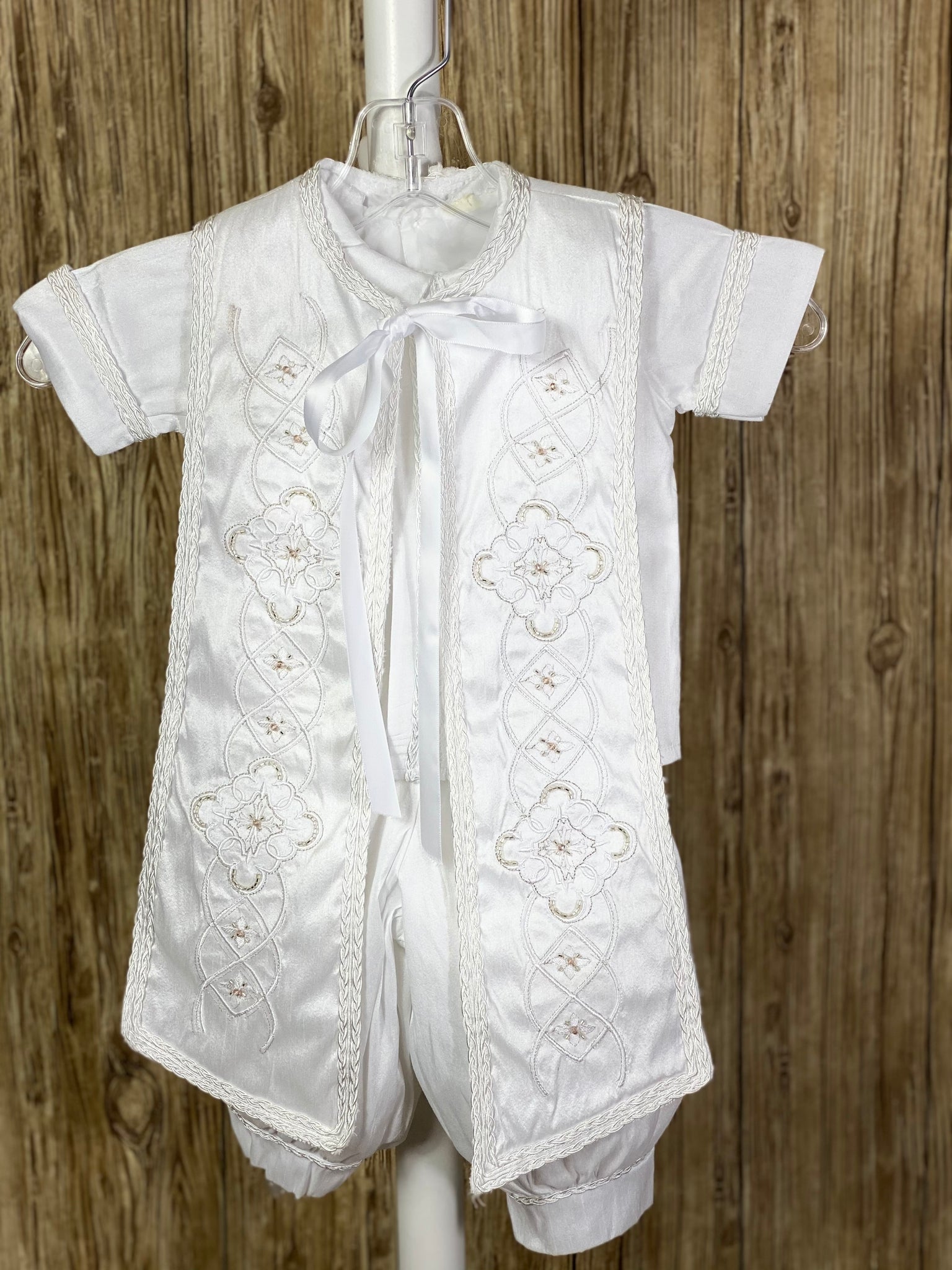 White, size 6M  4-piece set including shirt, pants, stole, beret Collared shirt with short sleeves Embroidered intricate design on stole, trimmed with braided ribbon around edge Ribbon closure on stole Intricate braided trim around beret Braided trim design on cuffs and shirt bodice Buttoning on pant cuffs Elastic banding behind pants Button closure on back of shirt
