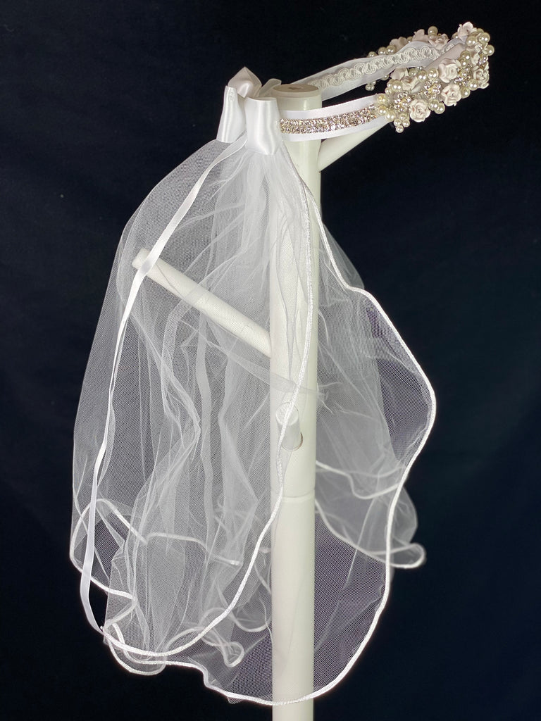 Elegant soft 2 layer tulle veil with delicate hand stitched braided satin trim around the edge and handmade flower halo crown with veil with large white satin bow on back. Ivory roses with rhinestone centers throughout crown band.  Beautiful rhinestone flowers with pearl detailing around crown band.  Rhinestone band around back side of crown.   This double layered veil reaches approximately 24" long, with a crown diameter of 6". Veil has 2" long, 3" wide, comb to secure it in place. 